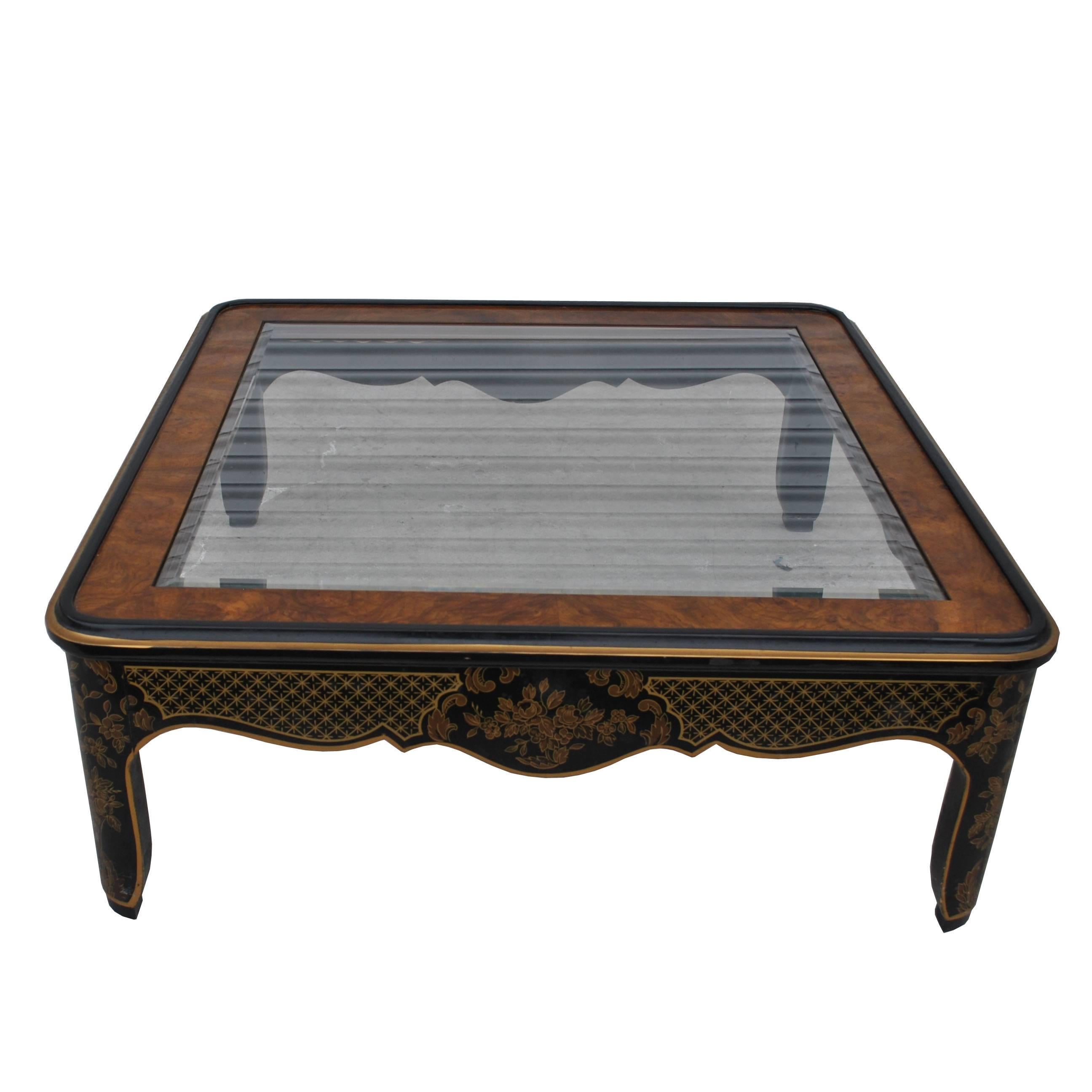 A square coffee table made by Drexel with Asian lines, decorated with Asian motifs, and a beveld glass top.