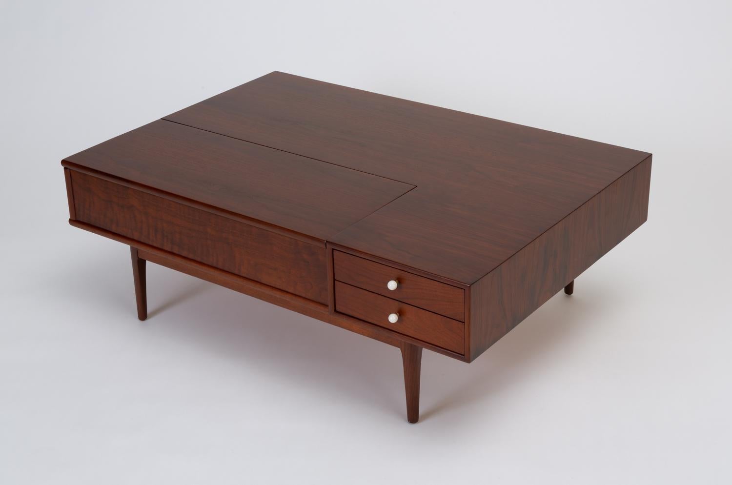 From the iconic Drexel Declaration collection by Kipp Stewart and Stewart MacDougall, this is a deep, rectangular table in walnut wood on recessed legs. Two drawers with signature porcelain drawer pulls sit in the right front corner, and a panel