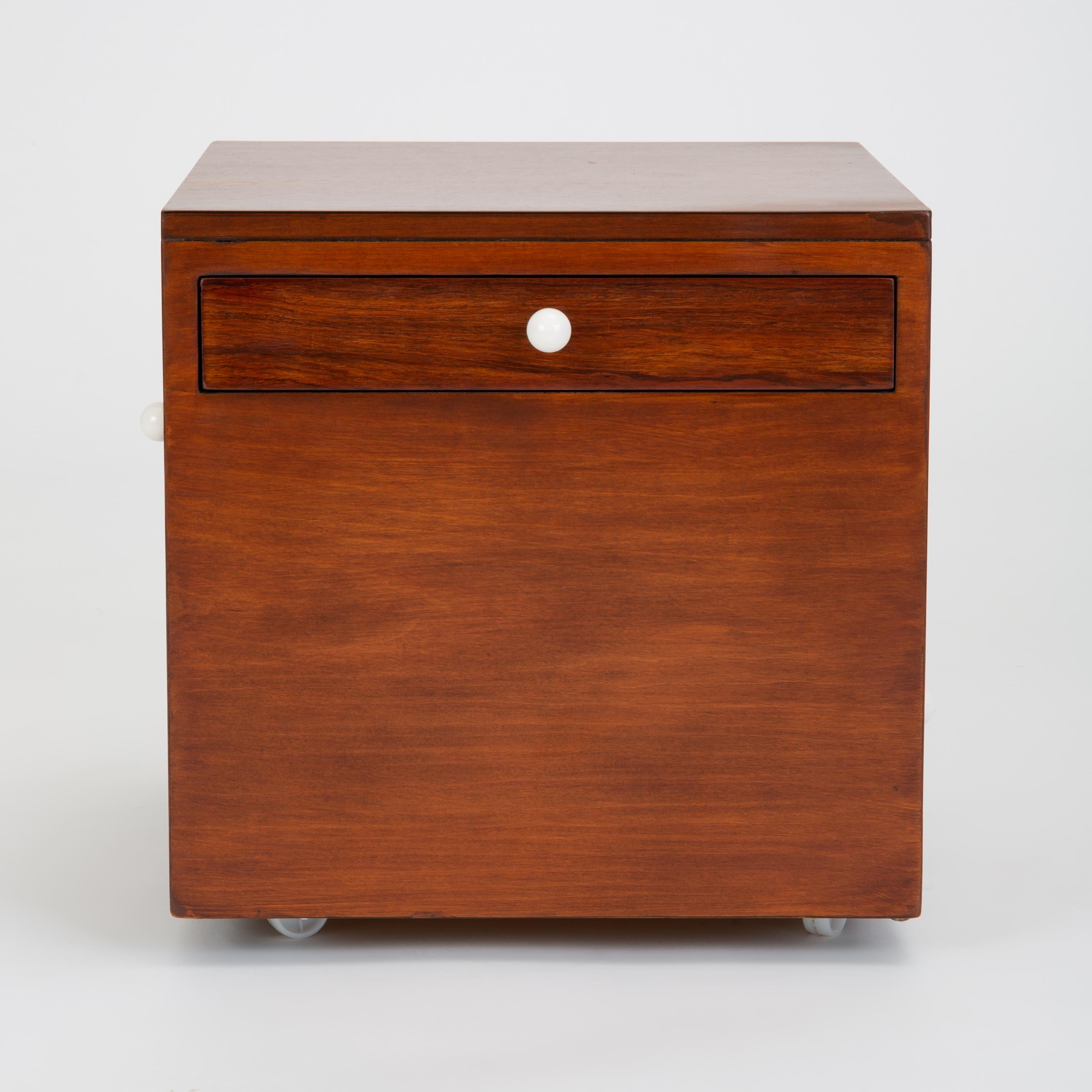 A model 881-314 mobile storage cube or side table from Drexel’s famed Declaration line features its signature walnut case and round porcelain drawer pulls. The modestly sized piece has a single, rosewood-panelled drawer in each of the four side