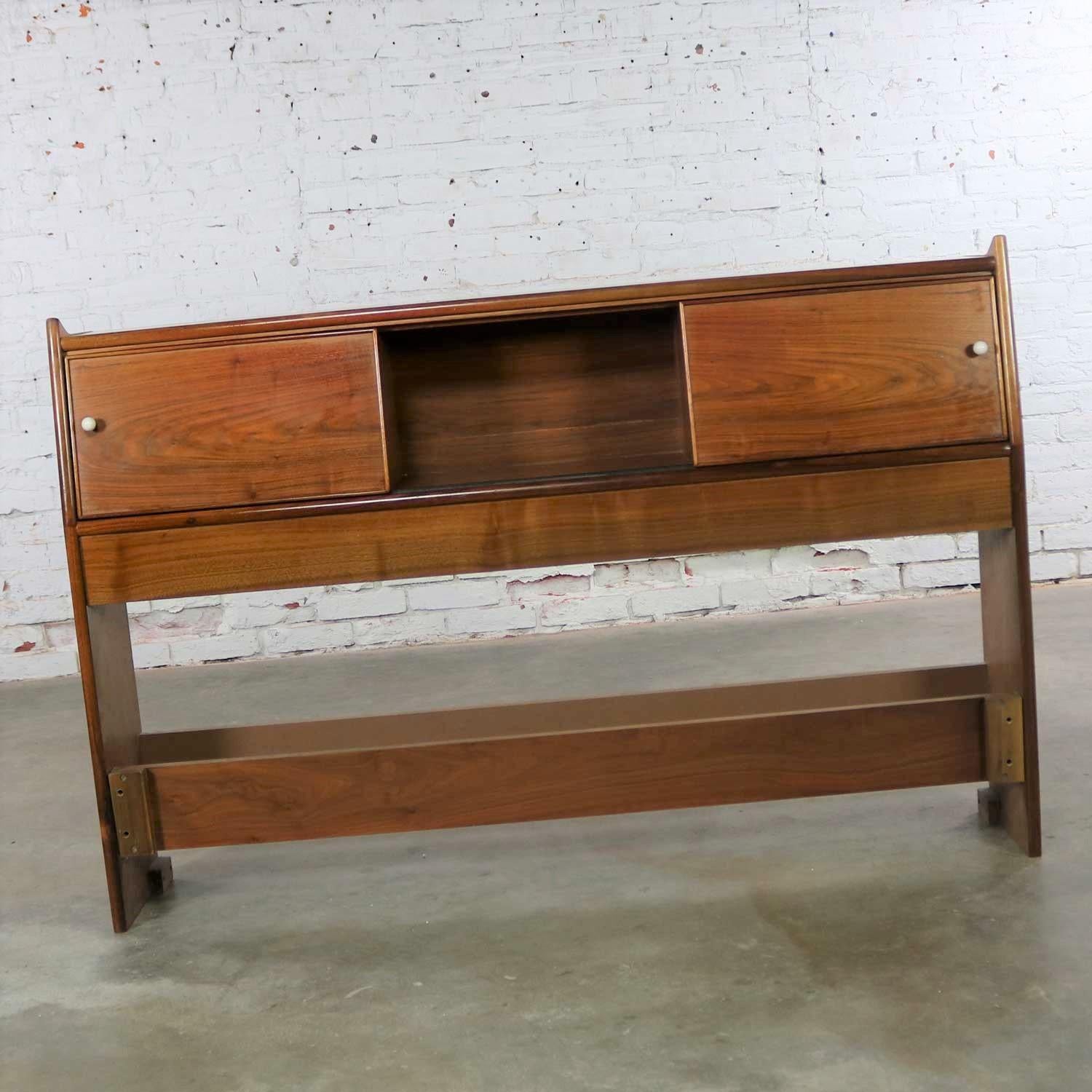 Handsome Mid-Century Modern walnut utility bookcase headboard with sliding cupboard doors 801-572-2 by Drexel from their Declaration collection designed by Kipp Stewart and Stewart MacDougall. It is in fabulous vintage condition overall. There is