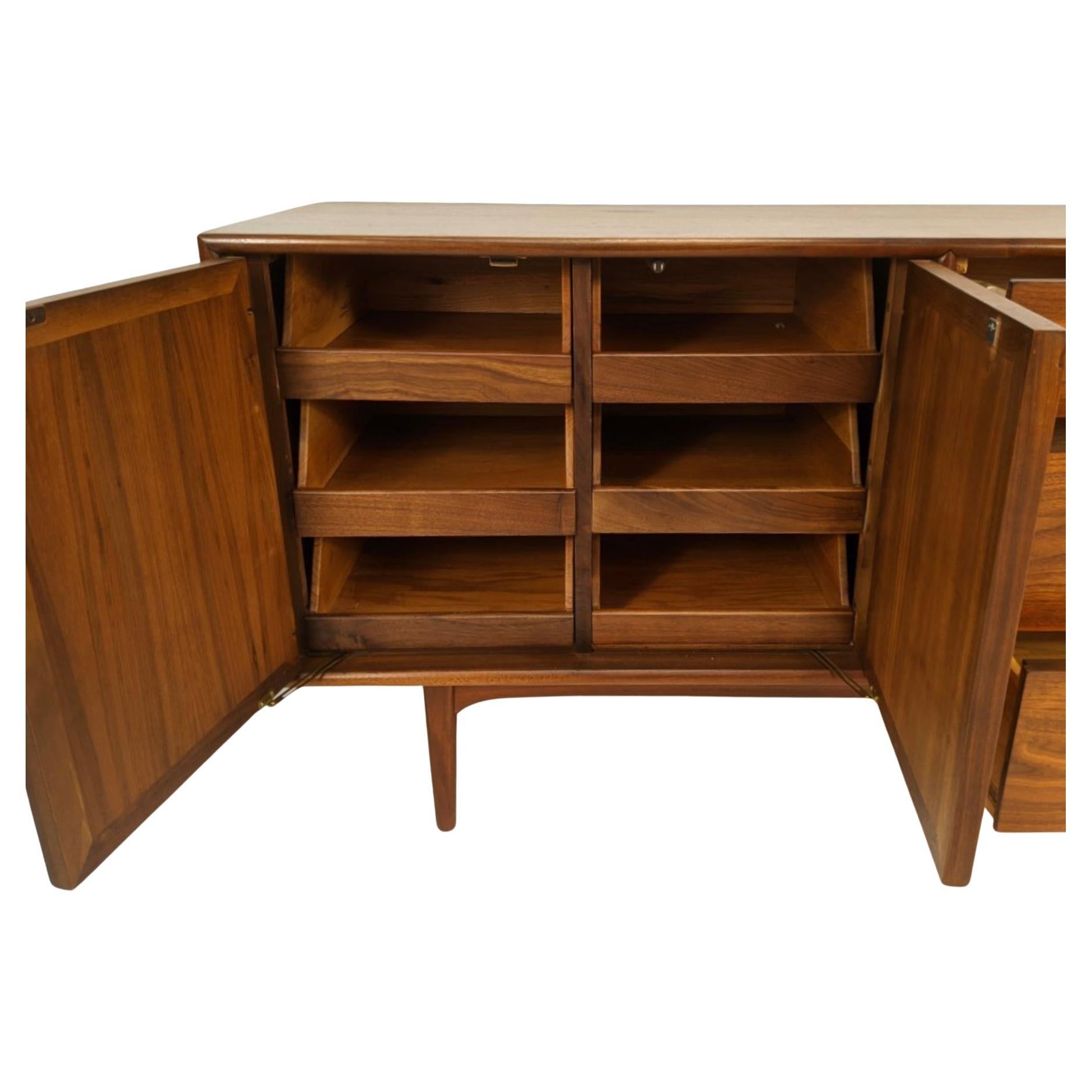 A gorgeous Mid-Century Modern walnut triple dresser from the desirable declaration line designed by Kipp Stewart and Stewart MacDougall for Drexel in the 1950s.  On the right are four smooth sliding drawers with original spherical white porcelain
