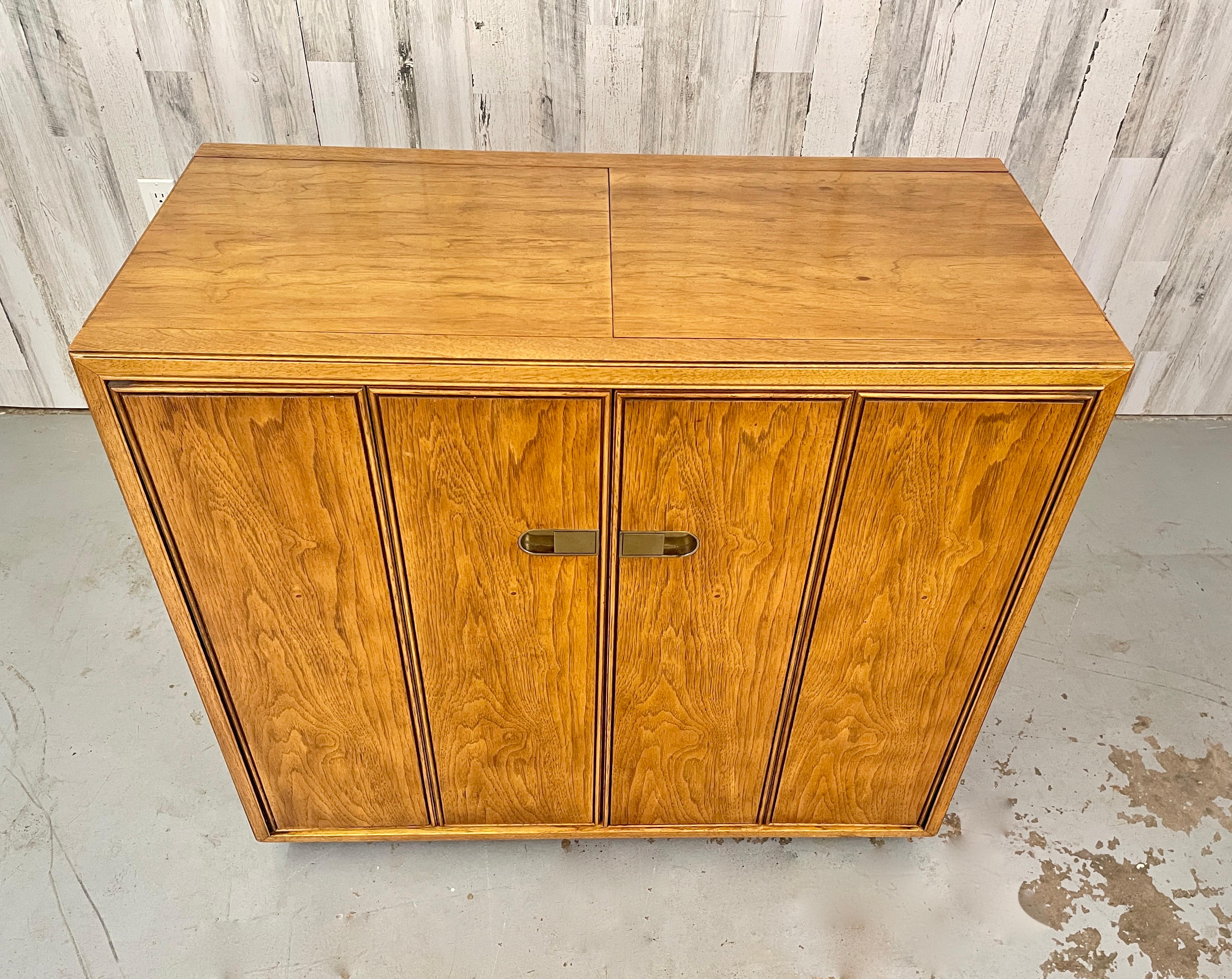 Drexel Extendable Top Liquor/Bar Cabinet with brass accents. This Piece has a nice finished back so it can easily be floated. This piece can be wheeled around a home with minimal effort- perfect for those who love to entertain! Width with both