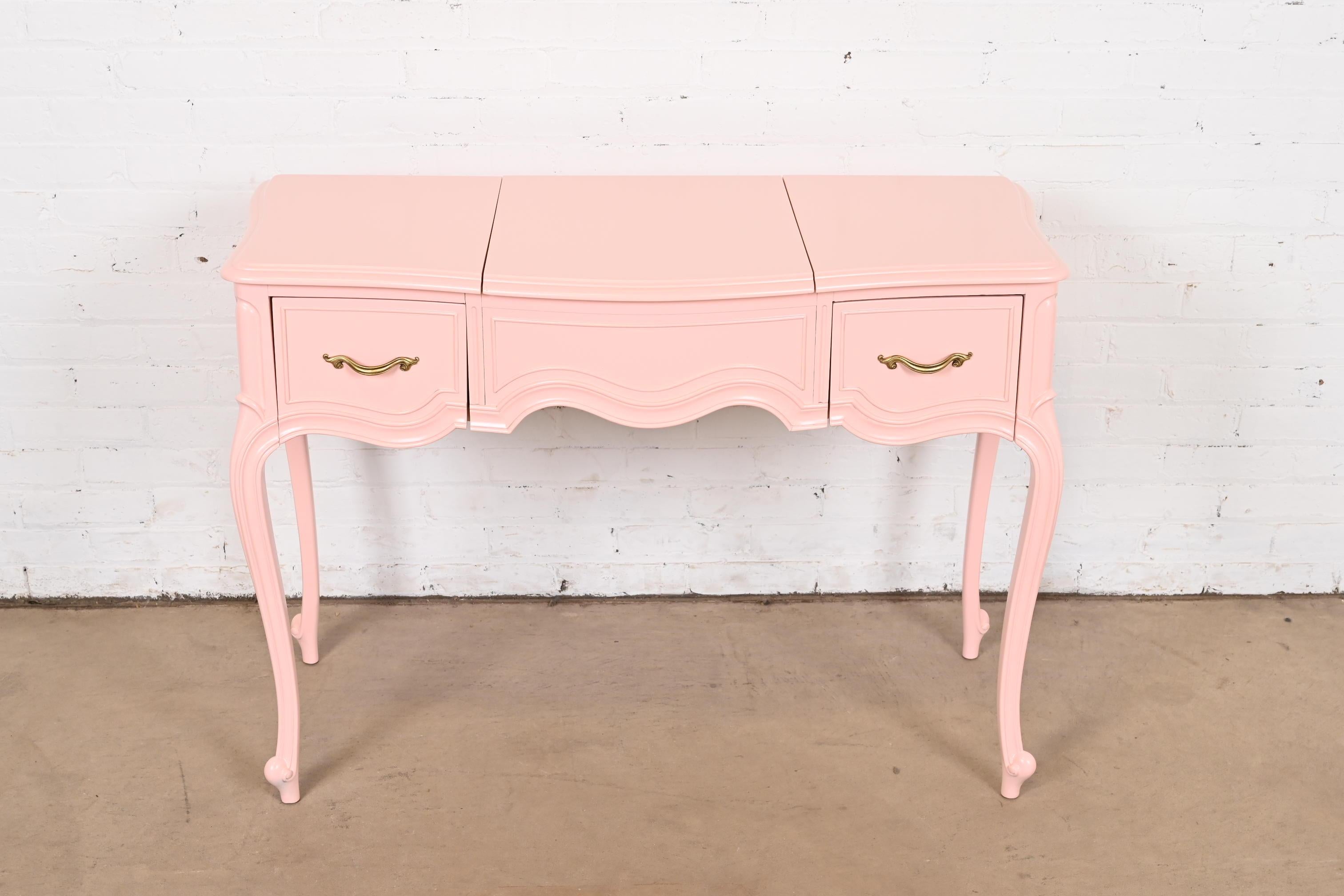 A gorgeous French Provincial Louis XV style vanity with flip up mirror

By Drexel

USA, Circa 1960s

Pink lacquered cherry wood, with original brass hardware.

Measures: 40.63