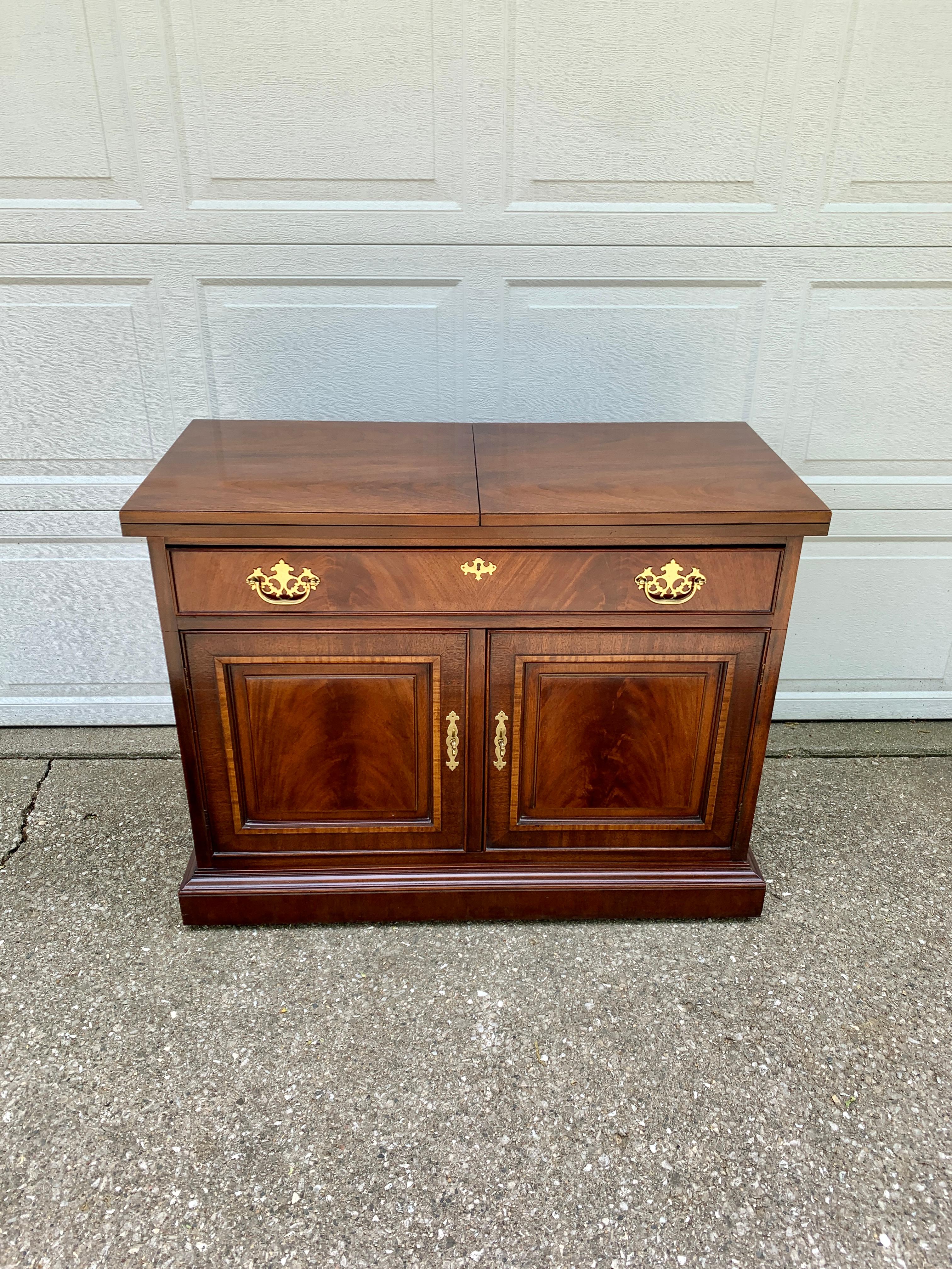 An exceptional Regency or Georgian style rolling server or bar cart with extending top

By Drexel

USA, Circa 1980s

Book-matched banded flame mahogany, with original brass hardware.

Measures: 40