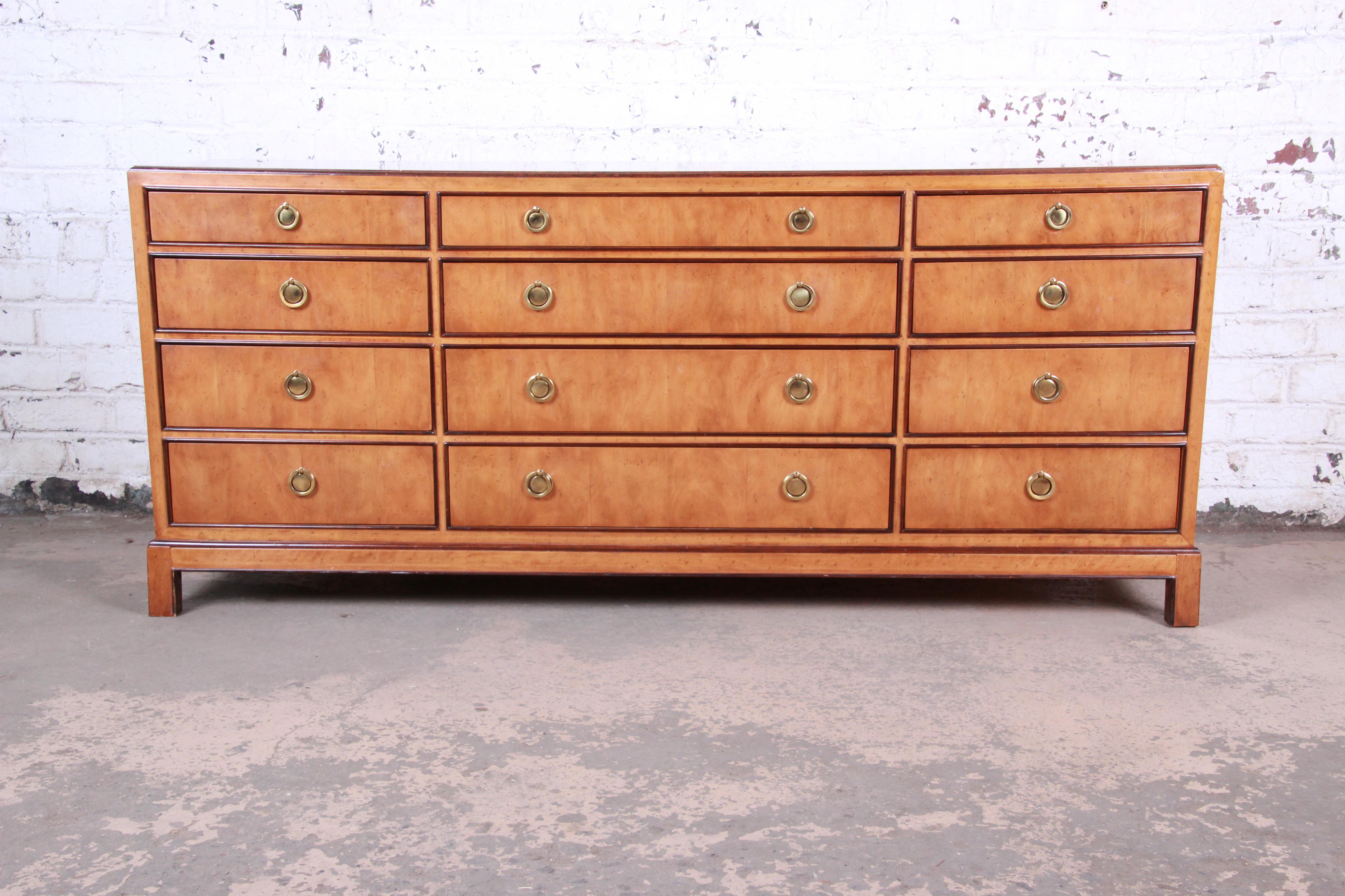 A gorgeous burl wood chinoiserie long dresser or credenza by Drexel Heritage. The dresser features stunning wood grain and clean lines, with a subtle Asian flair. It offers ample storage, with twelve dovetailed drawers each with original brass ring