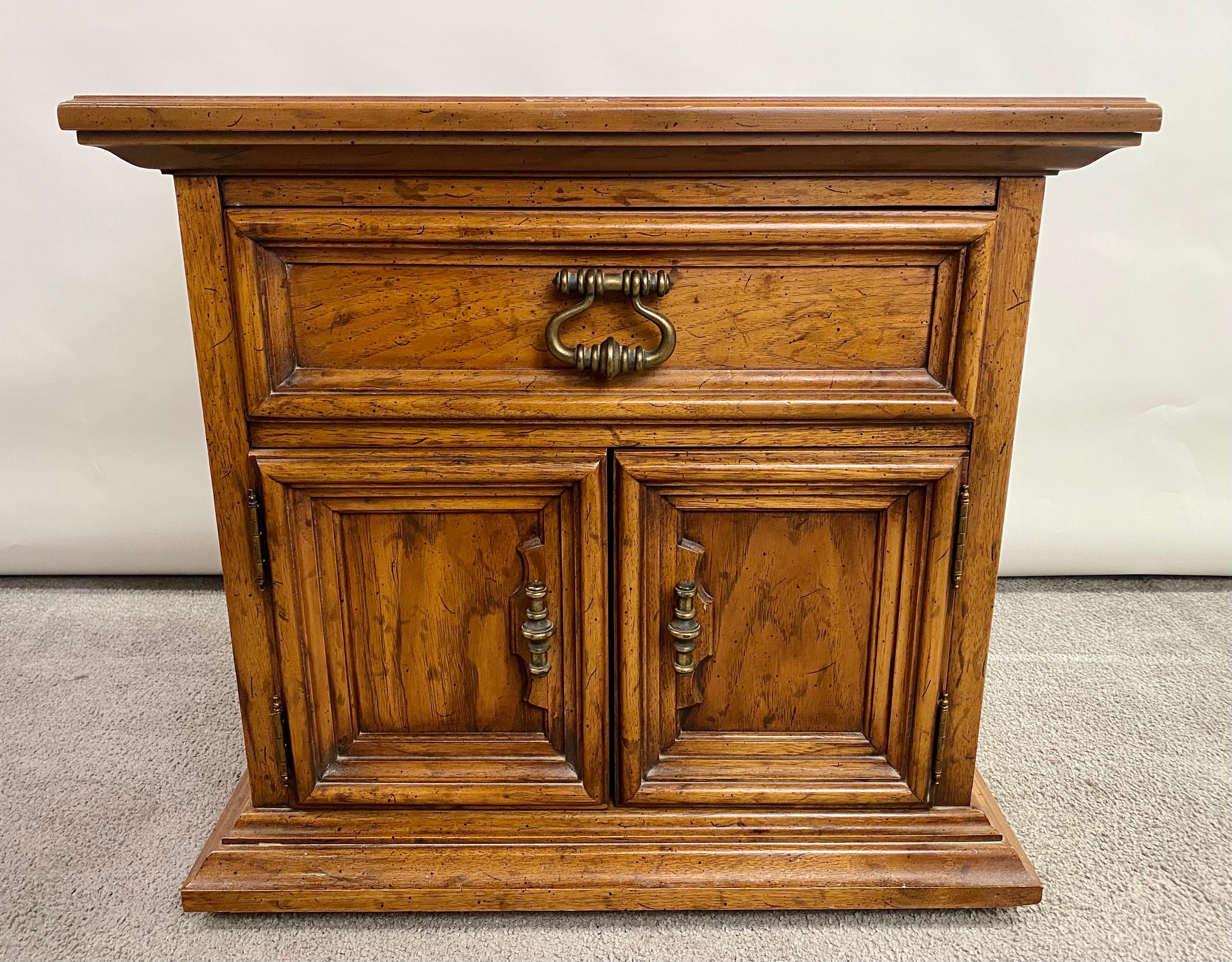 A high quality pair of nightstands by Dexel Heritage in campaign style. The Mid-Century pair of nightstands or end -tables are finely crafted of Pecan wood showing very nice wood grain. The nightstands feature a two door cabinet and one drawer for