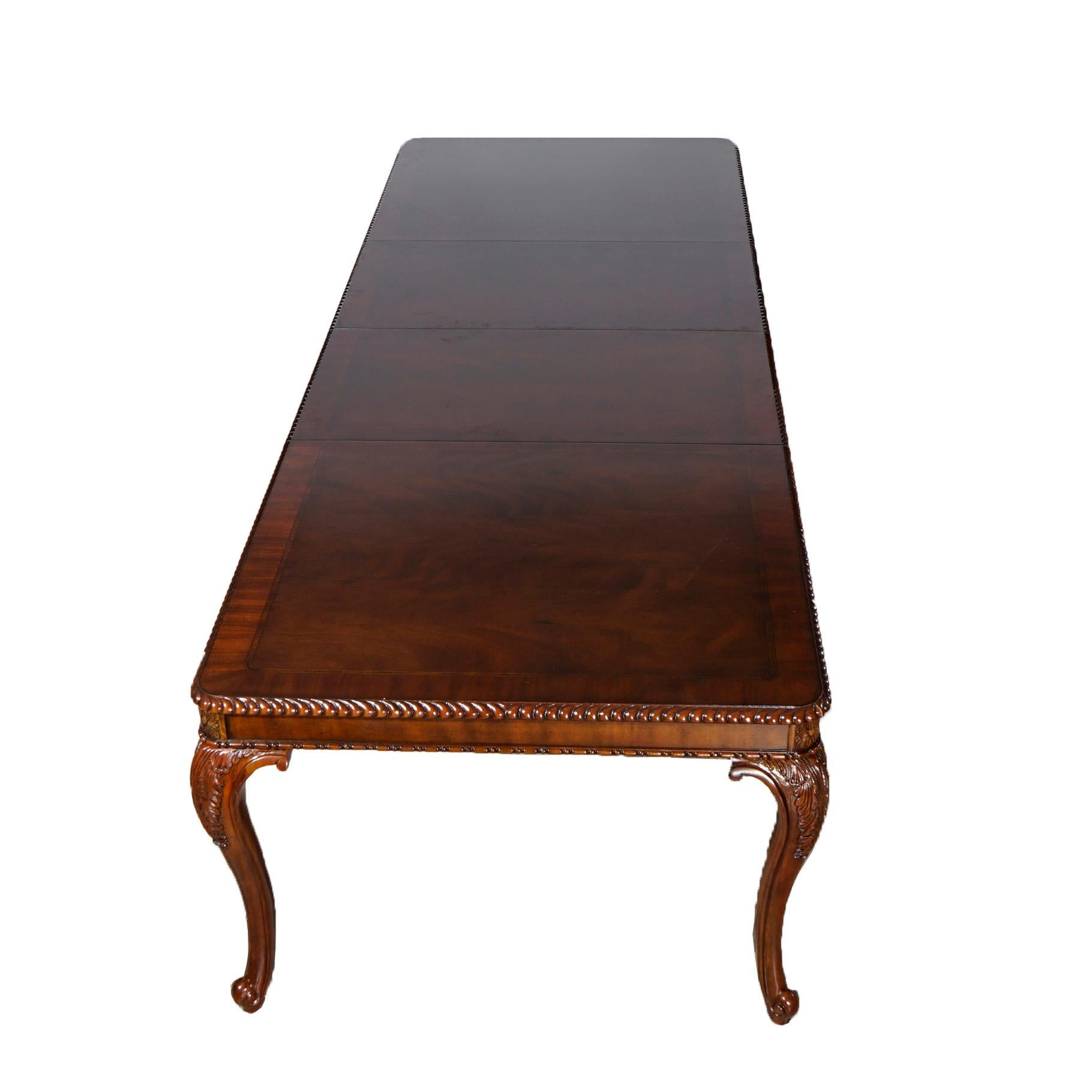 An extension dining table by Drexel of the Heritage Collection offers mahogany construction with inlaid satinwood banded top with carved rope twist trim raised on cabriole legs with carved acanthus knees, includes two leaves, 20th