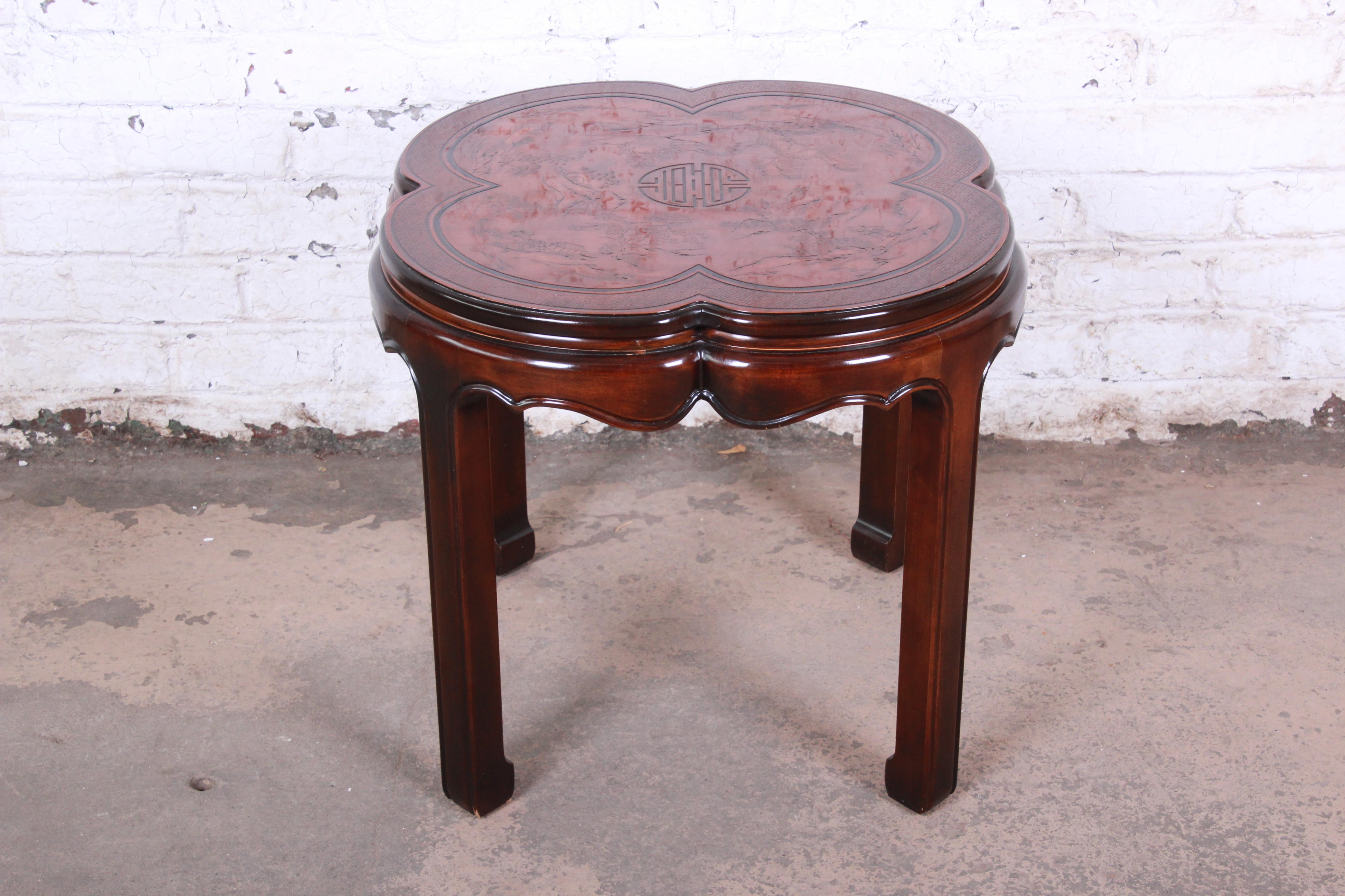 A gorgeous Hollywood Regency chinoiserie occasional table from the connoisseur line by Drexel Heritage. The table features beautiful mahogany wood grain, a unique clover shape, and nice carved Asian details with nature scenes. The table is in very