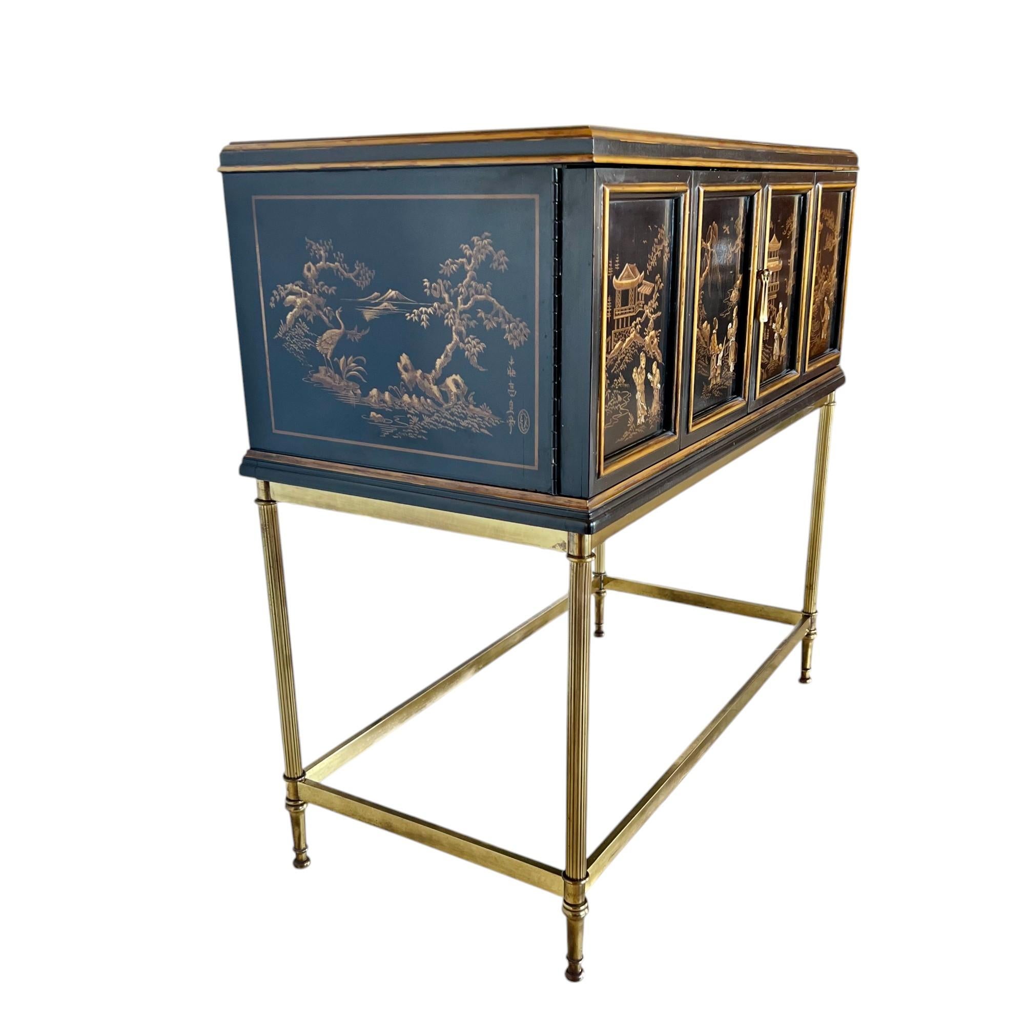 A gorgeous vintage Drexel Heritage chinoiserie petite two-door accent cabinet on a brass stand. This exceptional piece features a rectangular cabinet with a black lacquered finish and hand painted Asian scenes in gold and cream tones, gold detailing