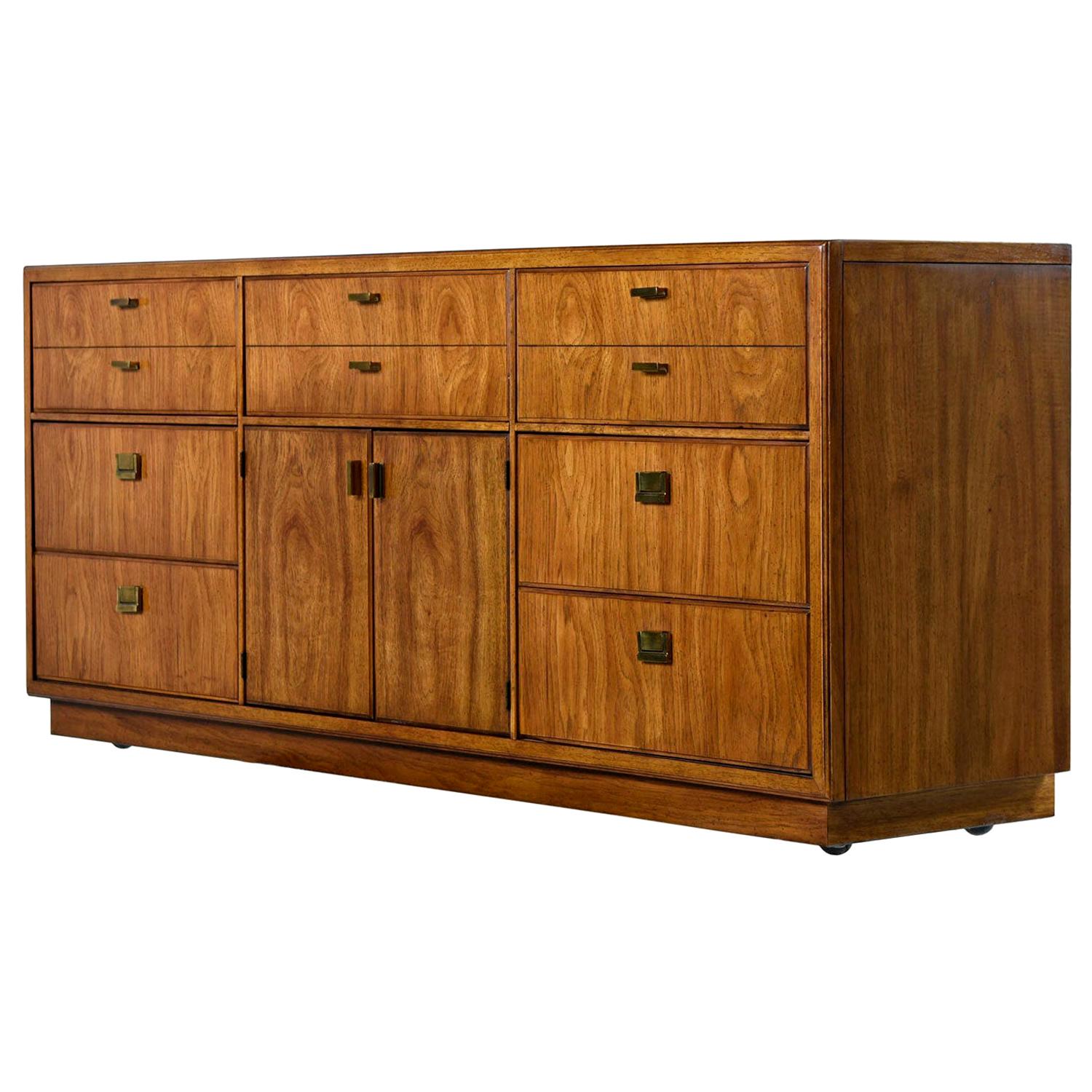 Dorothy Draper style campaign dresser made by esteemed US furniture maker Drexel Heritage, circa 1970s. Old growth flaxen flared grain pecan top to bottom. Brass pull hardware ties together British traditional and Eastern design. This dresser