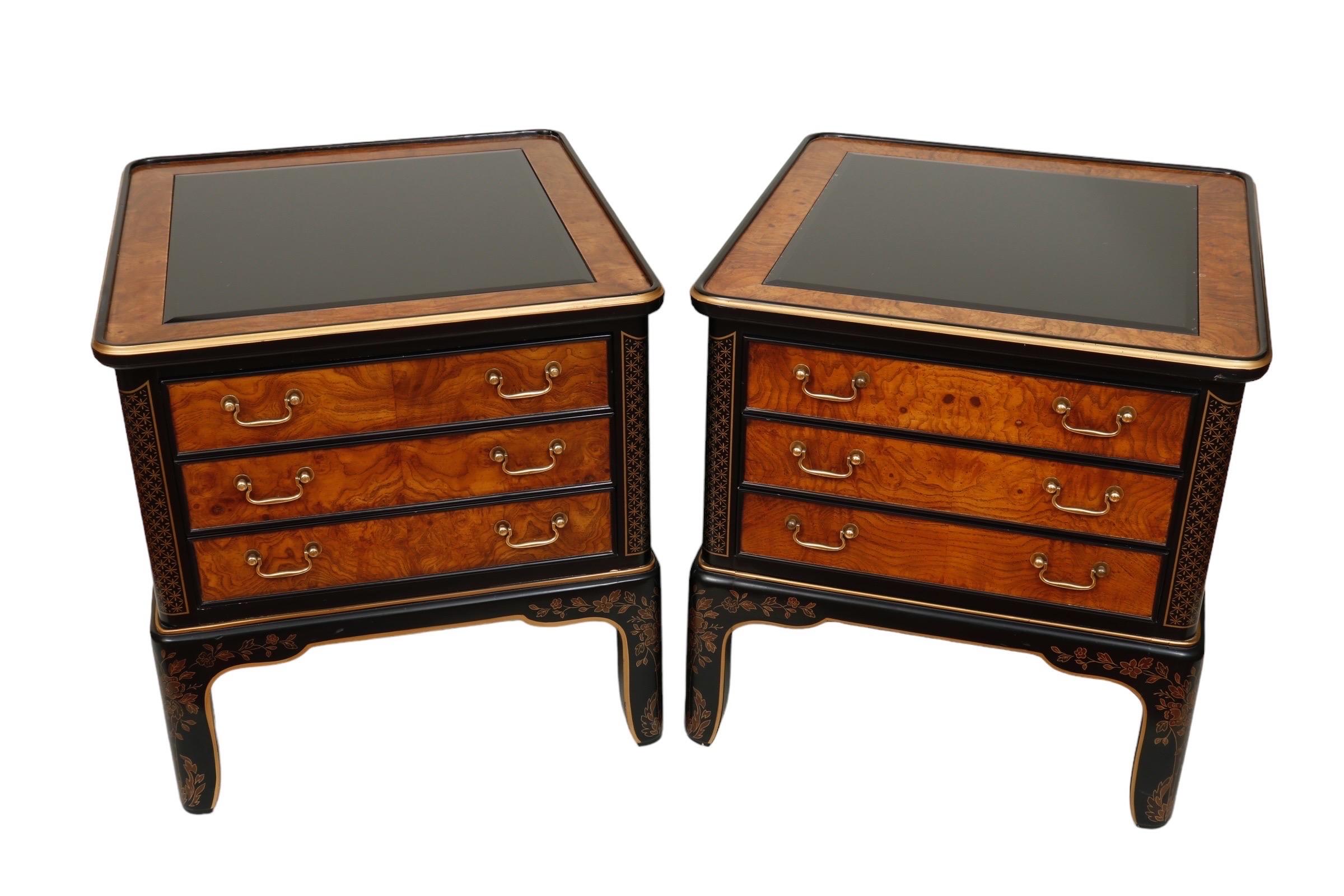 A matching pair of Drexel Heritage Chinoiserie side table cabinets from their Et Cetera collection. Beveled black glass tops are framed with a border of beautifully figured oak, raised edges trimmed in black and gold. Three dovetailed drawers,
