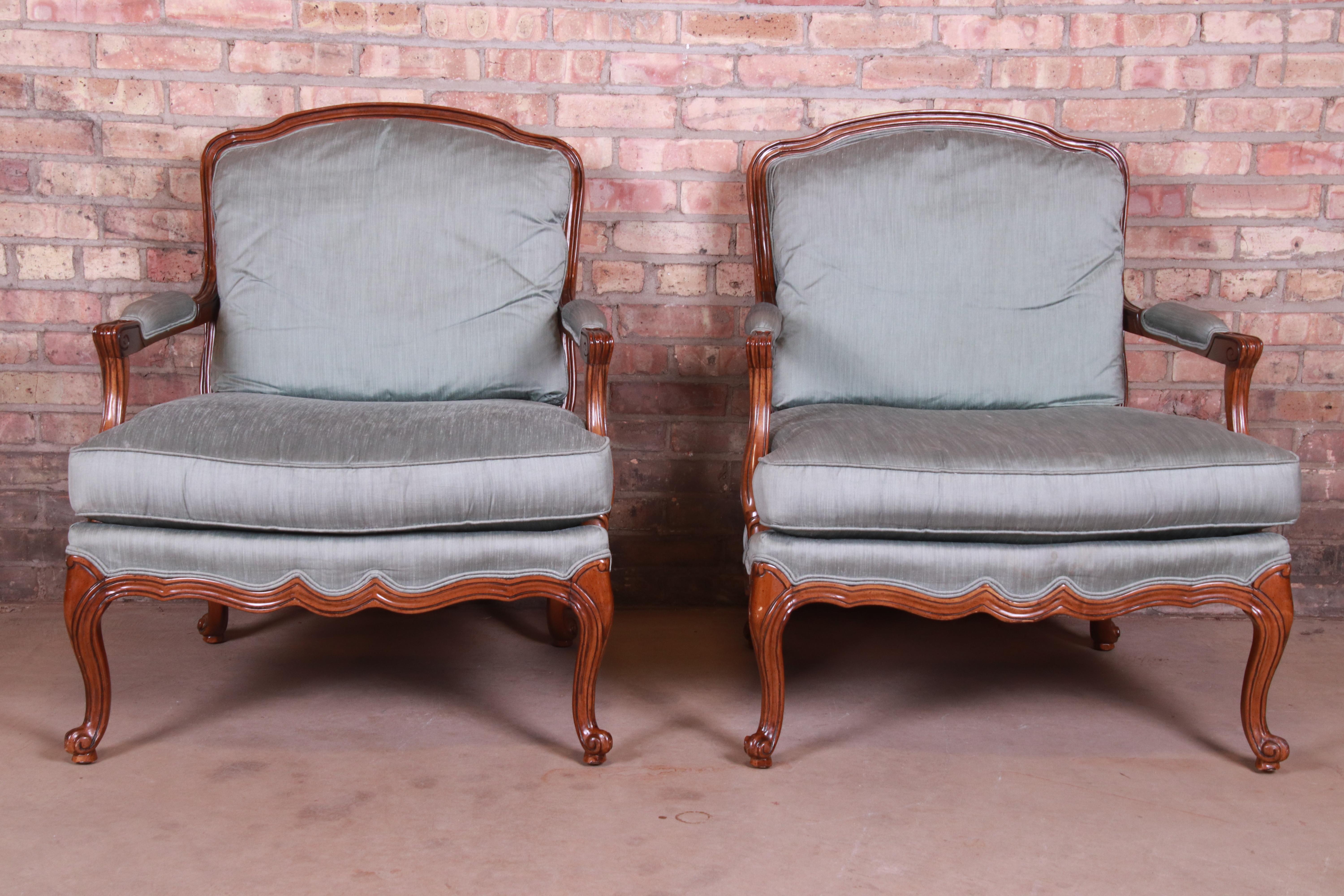 A gorgeous pair of French Provincial Louis XV style upholstered bergère or lounge chairs.

By Drexel Heritage

USA, Late 20th century

Carved walnut, with upholstered seats and backs and down-filled cushions.

Measures: 29.25