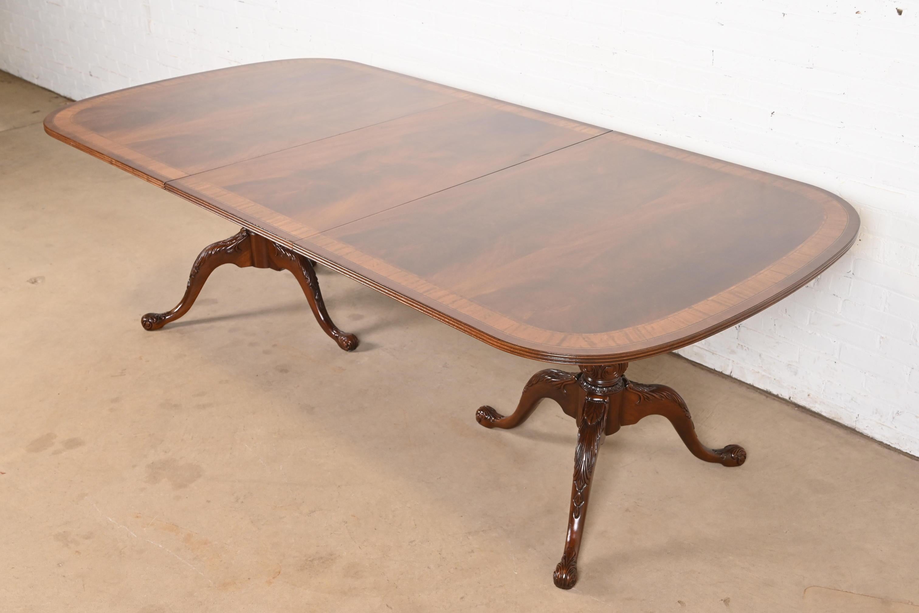 Exceptionnelle table de salle à manger à double piédestal de style géorgien ou Chippendale.

Par Drexel Heritage

USA, Circa 1980

Magnifique plateau en acajou flammé assorti aux livres, avec bandes en bois satiné, et piédestaux en acajou massif