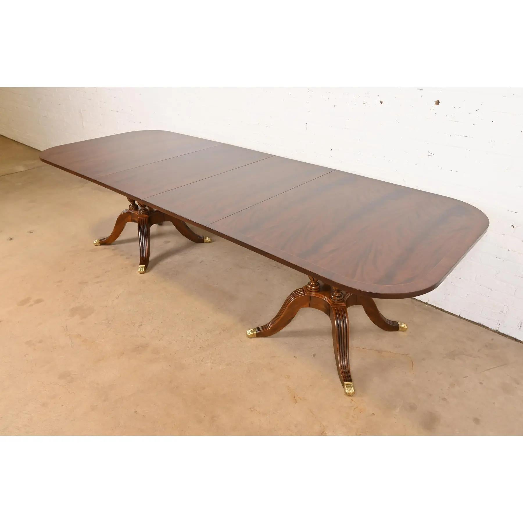 Un eccezionale tavolo da pranzo allungabile a doppio piedistallo in stile Georgiano o Regency

Da Drexel Heritage

USA, circa anni '1980

Splendido piano in mogano a fiammella accoppiato a libro, con intarsio di corde in legno di raso, piedistalli