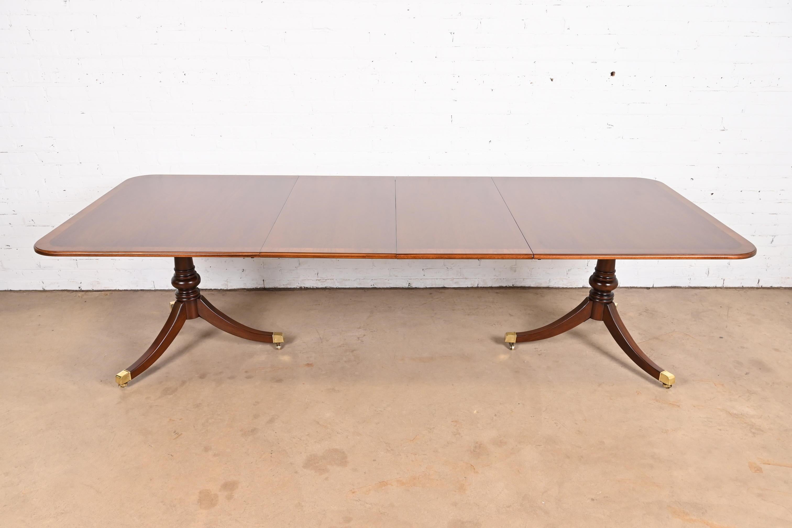 Exceptionnelle table à manger à rallonge à double piédestal de style Géorgien ou Régence.

Par Drexel Heritage

USA, Circa 1980

Magnifique plateau en acajou bagué, avec des piédestaux en acajou sculpté, et des pieds coiffés de laiton sur des