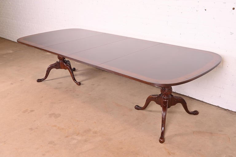 An exceptional Georgian or Chippendale style double pedestal extension dining table

By Drexel Heritage

USA, Circa 1980s

Book-matched flame mahogany, with satinwood banding, and carved solid mahogany pedestals.

Measures: 74
