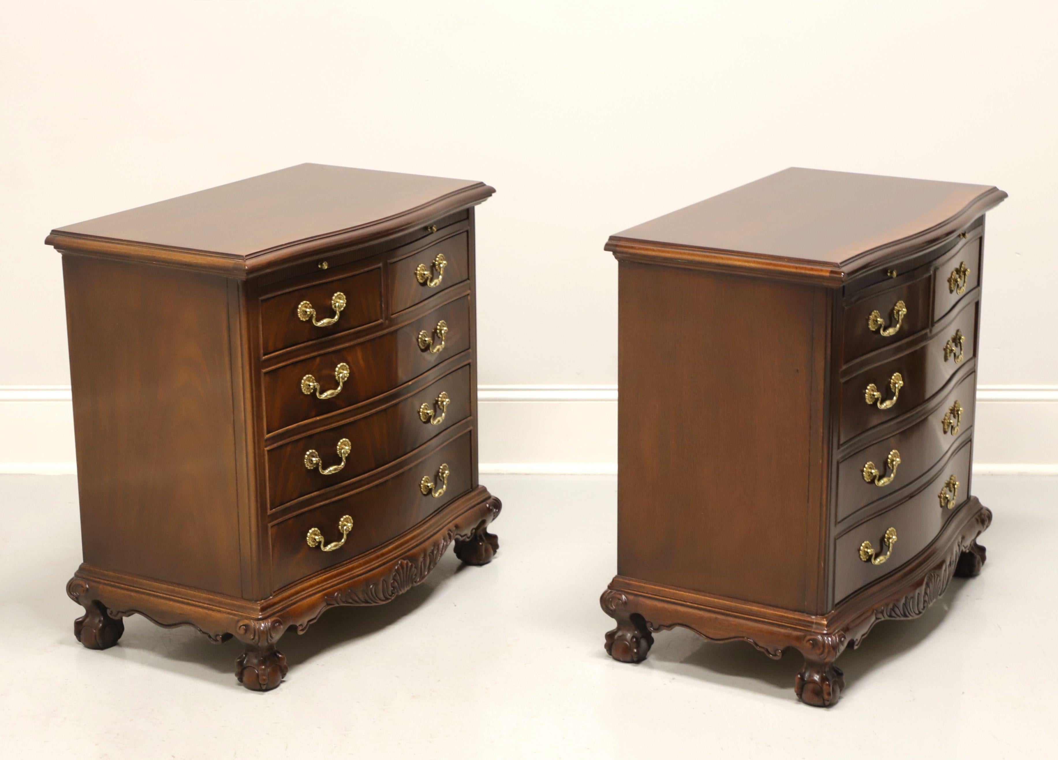 A pair of Chippendale style nightstands by Drexel Heritage, from their Heirlooms Collection. Flame mahogany with serpentine front, brass hardware, decoratively carved apron with center shell, carved knees and ball in claw feet. Features a pull out