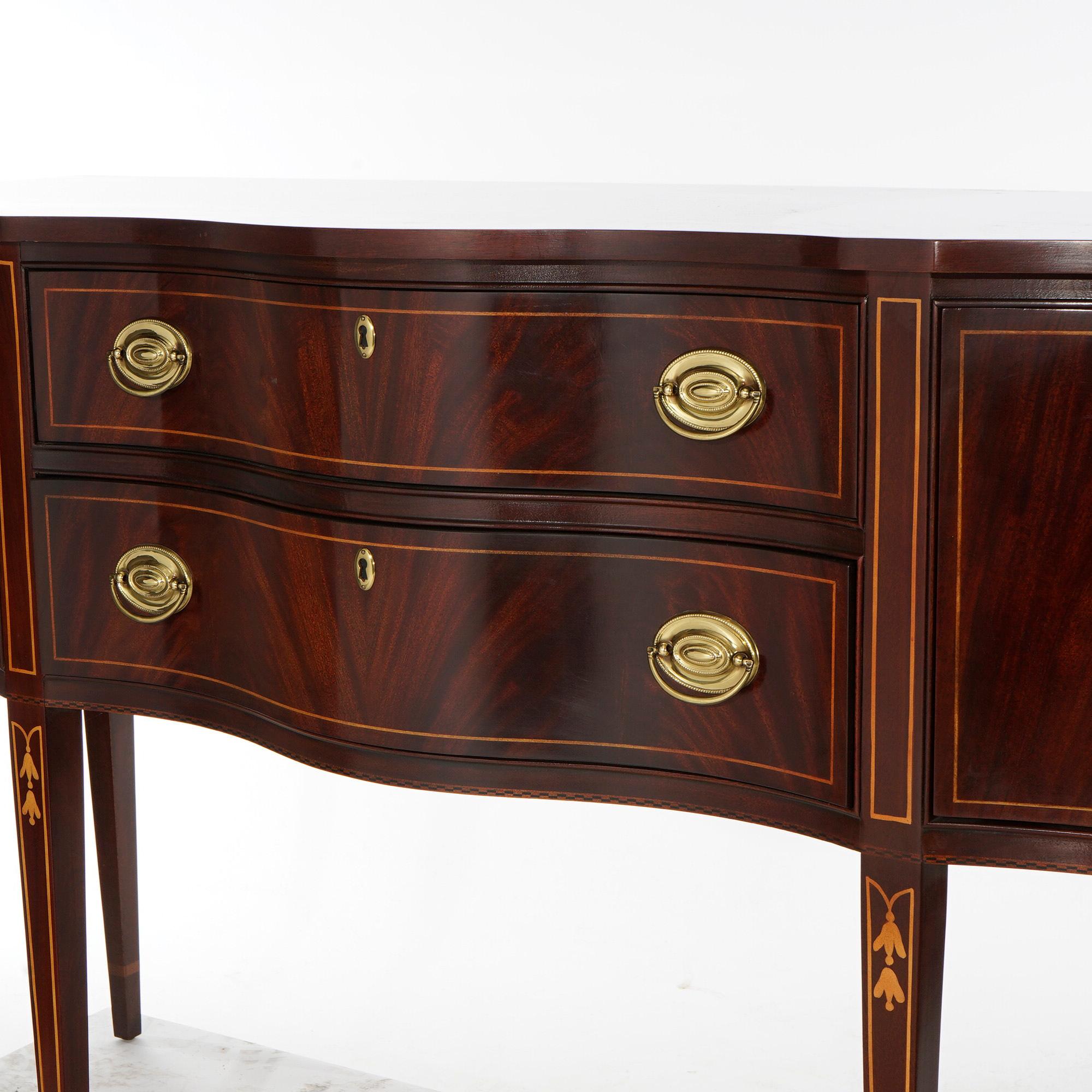 A Hepplewhite style sideboard by Drexel Heritage offers flame mahogany construction in serpentine form with central drawers and flanking cabinets, raised on straight tapered legs, satinwood inlaid banding throughout, maker mark on drawer interior as