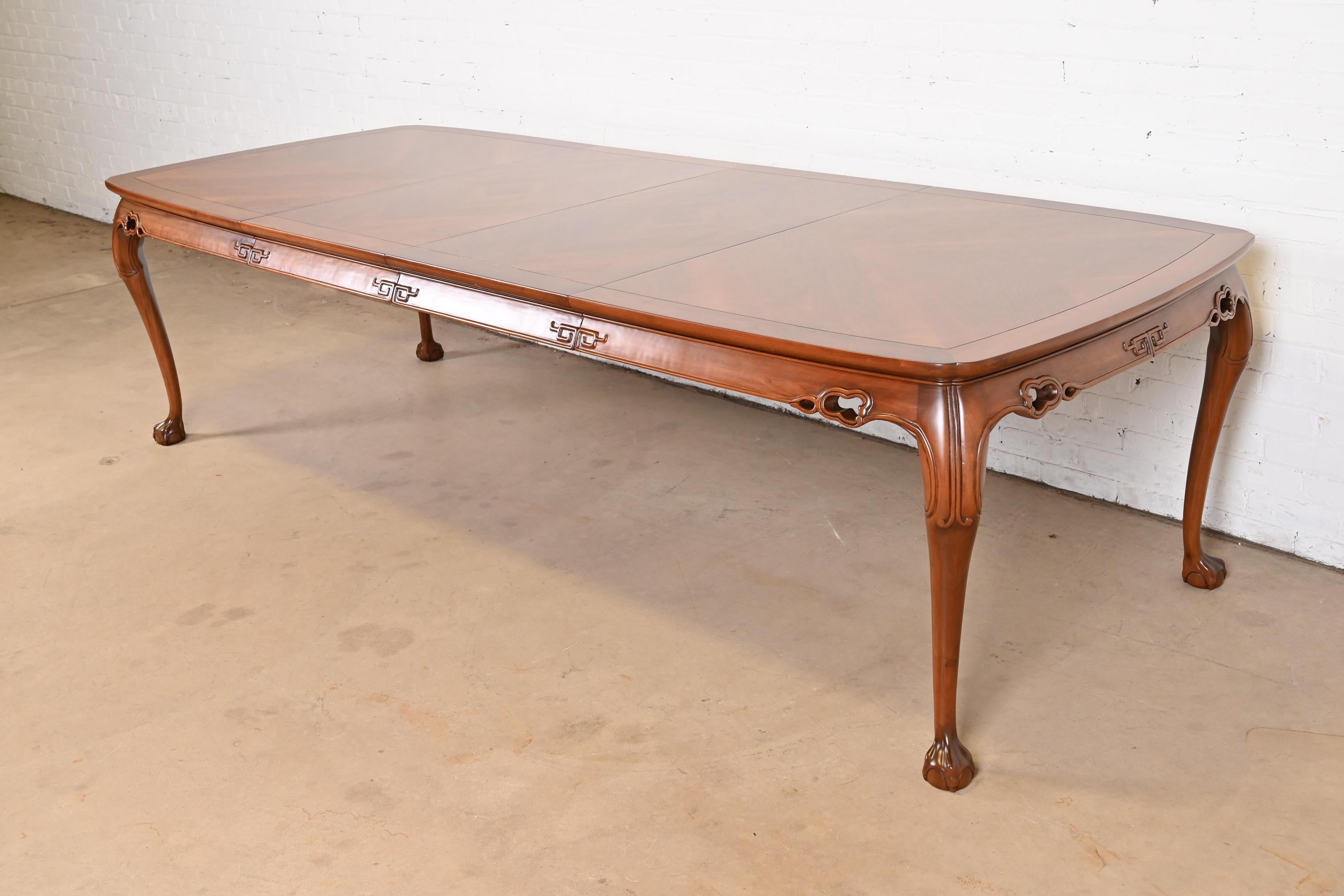 An exceptional mid-century modern Hollywood Regency Chinoiserie extension dining table

By Drexel Heritage

USA, Circa 1970s

Gorgeous book-matched inlaid walnut top, with solid walnut base featuring carved Asian designs on legs and apron, and ball