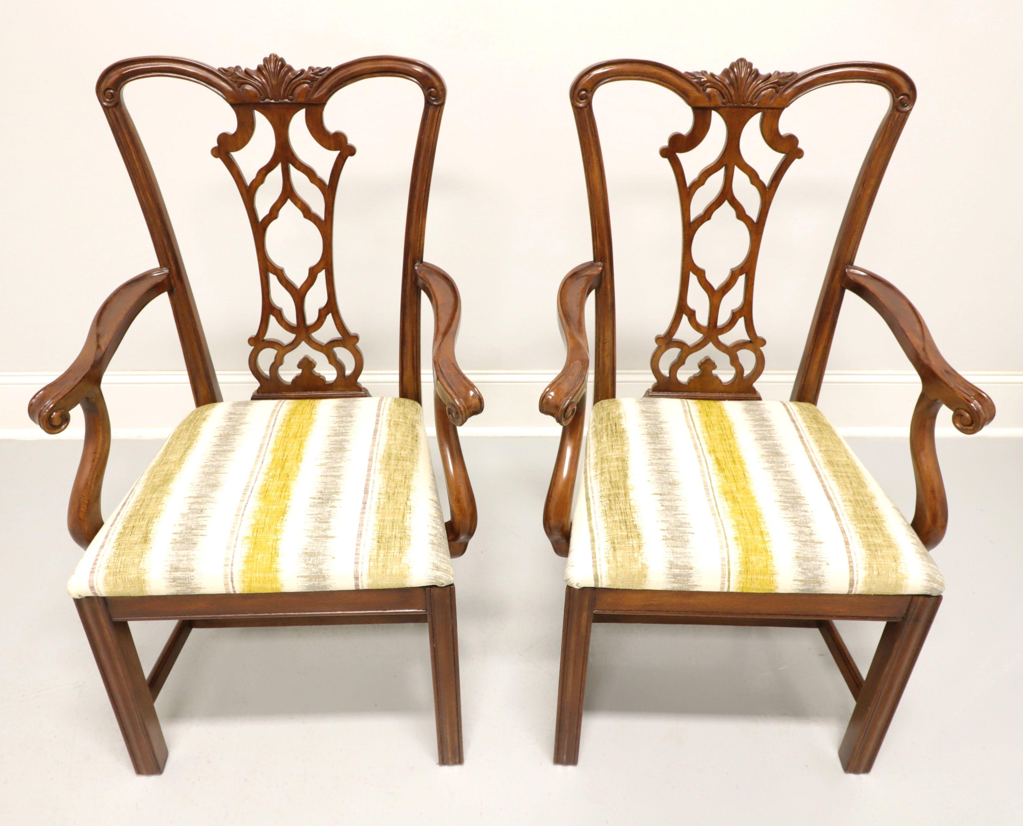 A pair of dining armchairs in the Chippendale style by Drexel Heritage. Solid mahogany with carved crest rail, curved arms, carved seat back, gray/yellow-green/green-gray/cream color stripe pattern upholstered seat, straight legs and stretchers.