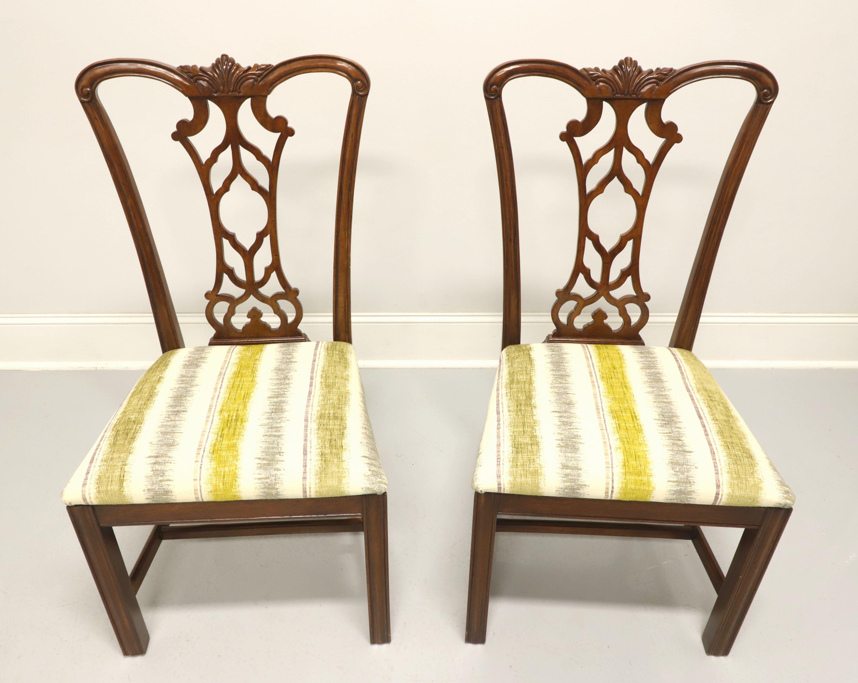 A pair of dining side chairs in the Chippendale style by Drexel Heritage. Solid mahogany with carved crest rail, carved seat back, gray/yellow-green/green-gray/cream color stripe pattern upholstered seat, straight legs and stretchers. Made in
