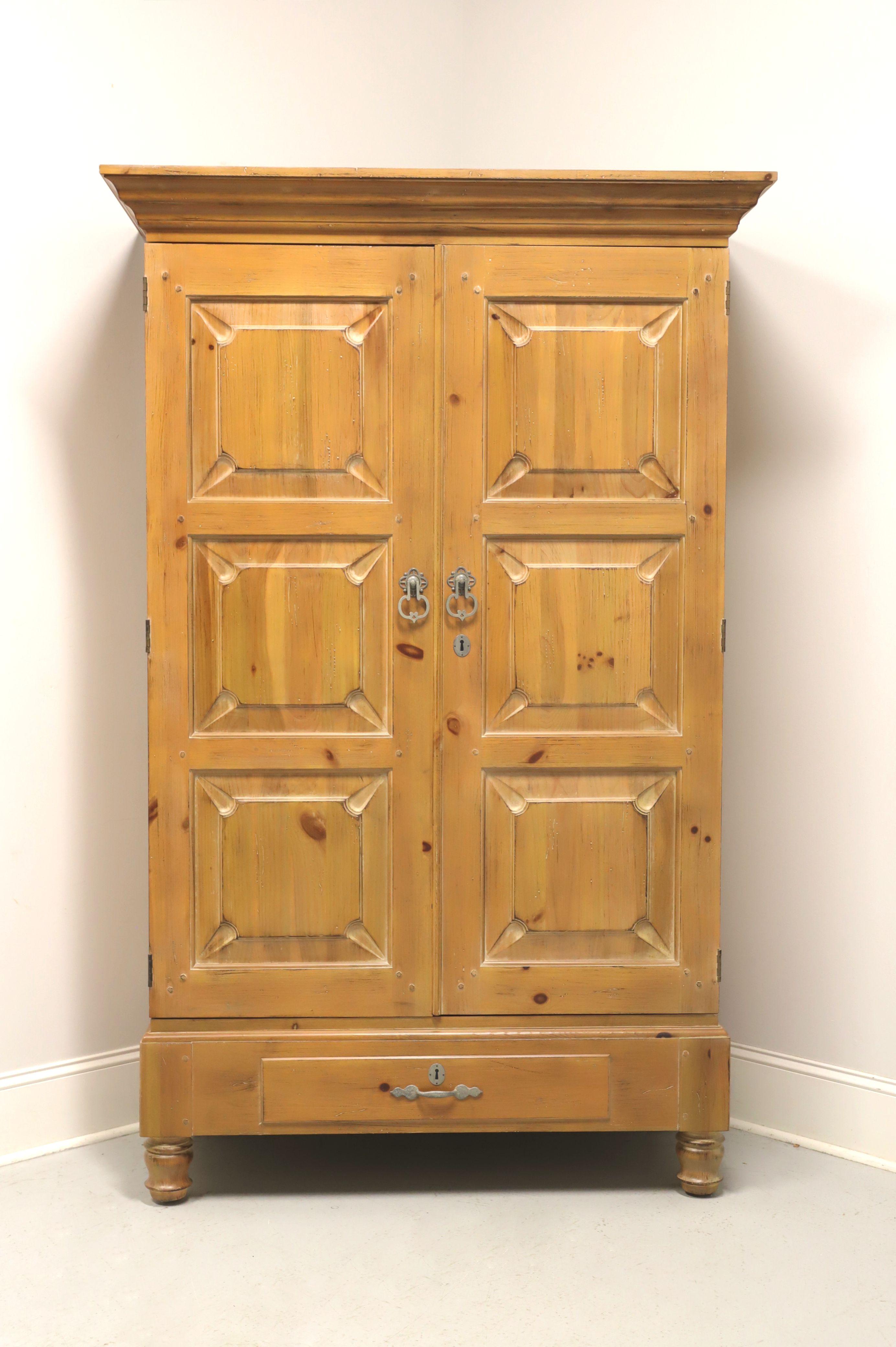 A Spanish Mission style armoire / linen press by Drexel Heritage, from their Sonora Collection. Solid pine with an antiqued finish, metal hardware, crown molding, raised panel doors and bun feet. Upper cabinet features double doors revealing an