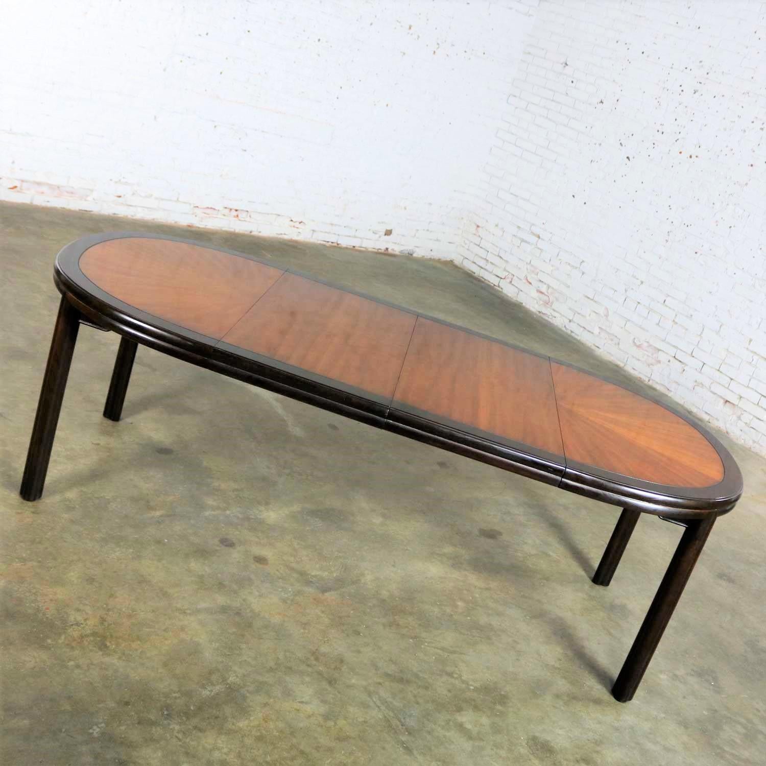 Handsome two-toned Ming style oval dining table with two aproned leaves and faux bamboo legs and edge by Drexel in the style of Chin Hua. It is in wonderful vintage condition with normal wear for its age including slight scratches to finish but