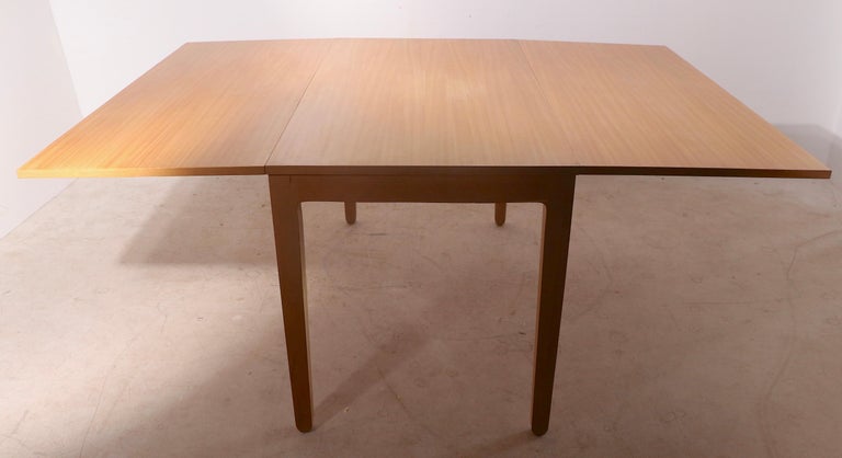 Attractive white elm drop leaf dining table, designed by Edward Wormley as part of the classic Precedent series, manufactured by Drexel. The table features two large drop leaves, each 22 inches W allowing the bale to be a relatively small dining