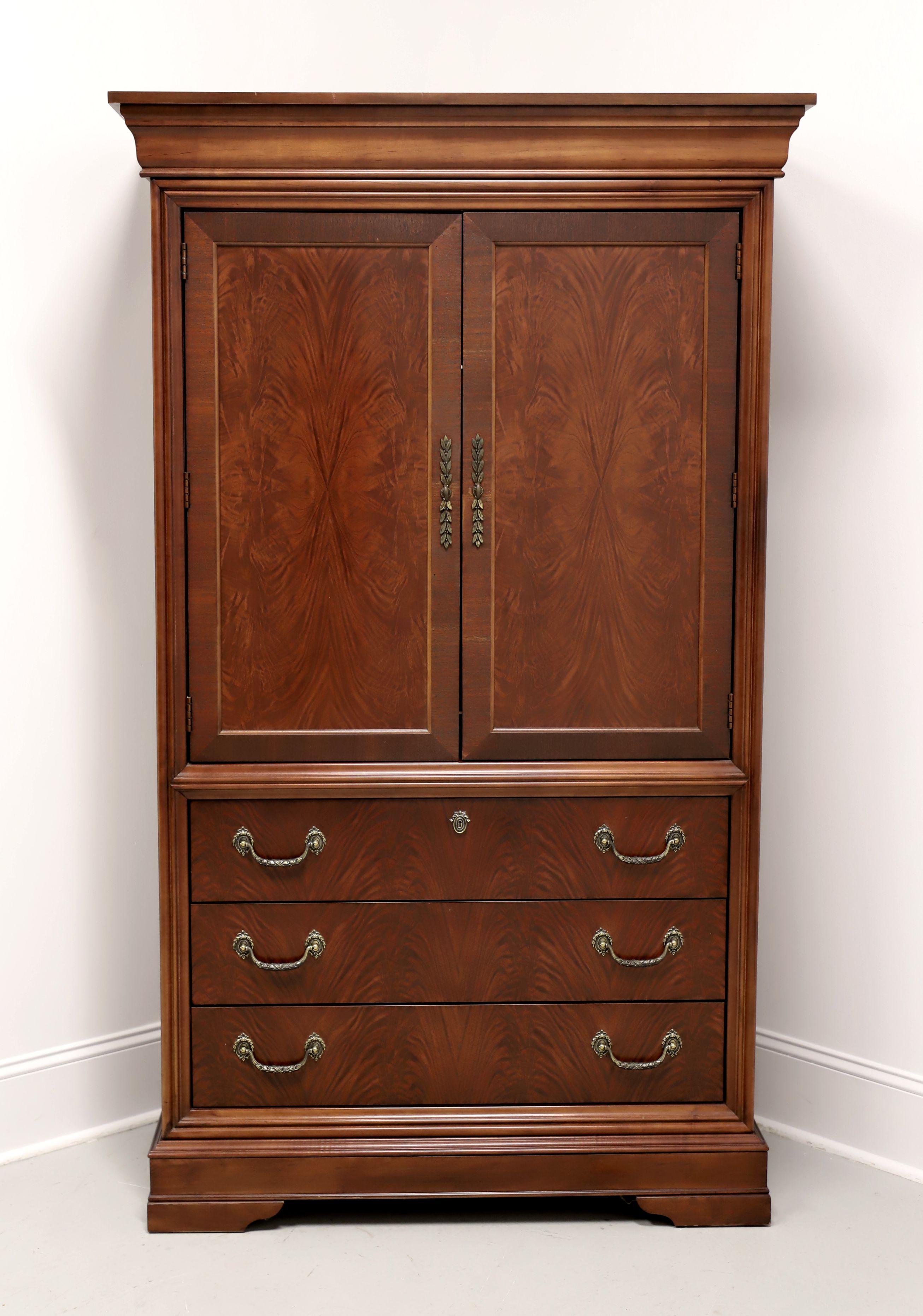An armoire / linen press in the French style by Drexel Studio, from their Marseille Collection. Mahogany with flame mahogany door & drawer fronts, decorative brass hardware, crown molding, banded door fronts, and bracket feet. Upper cabinet features