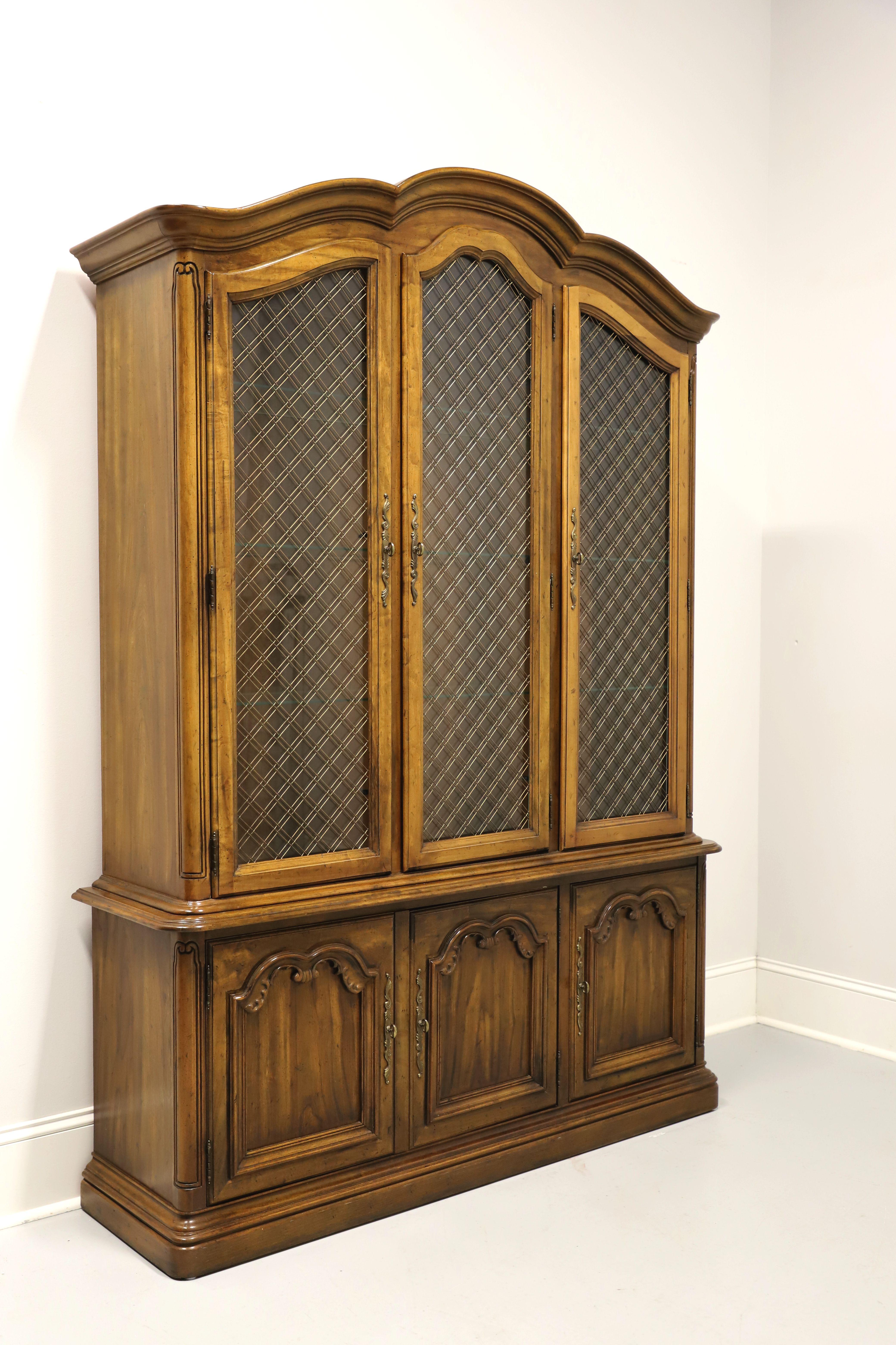 A china display cabinet in the French Country style by Drexel, from their Touraine II Collection. Pecan, or similar nutwood, brass hardware, arched top with crown molding, decoratively carved details, rounded corners, and solid base. Upper cabinet