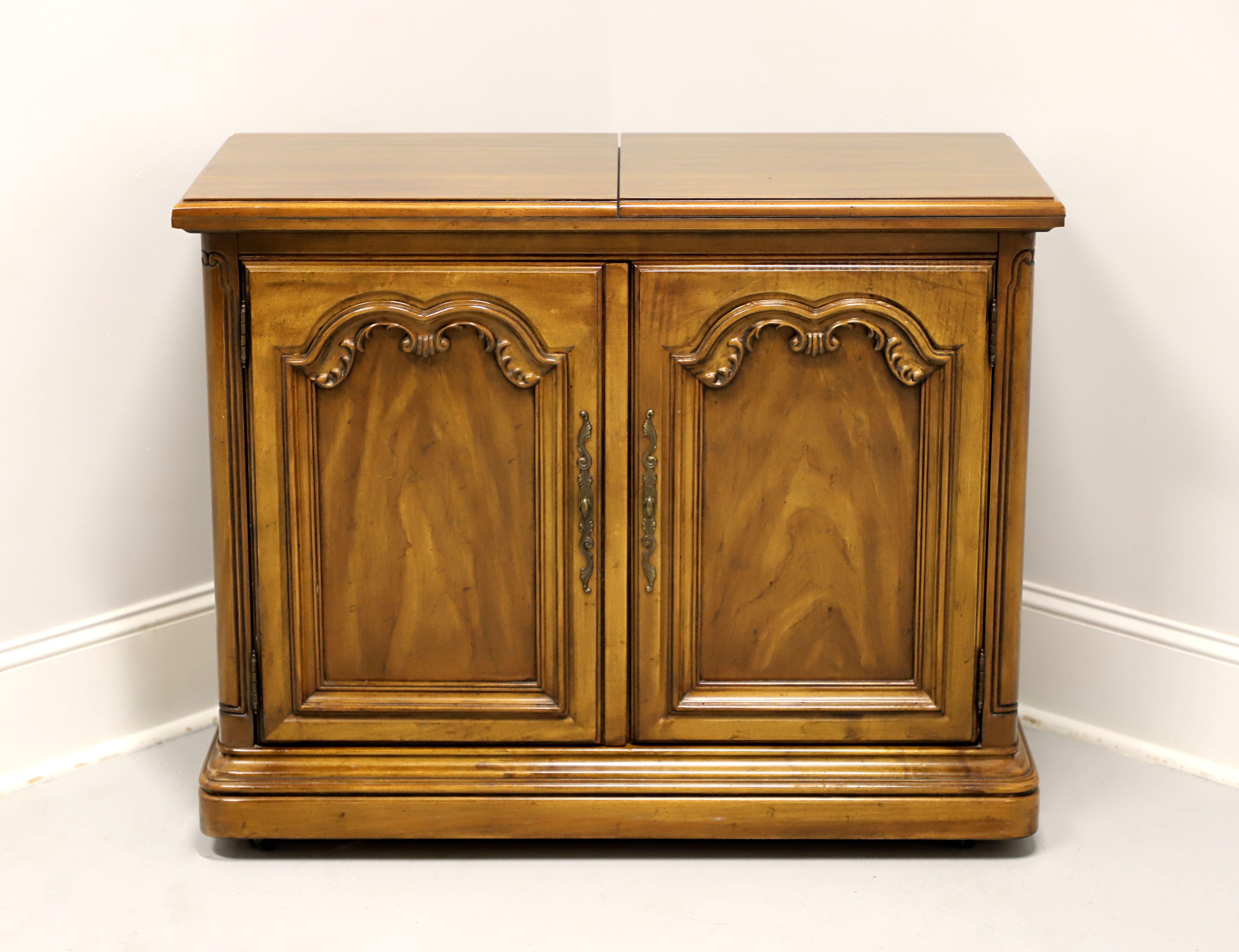 A flip top server in the French Country style by Drexel, from their Touraine II Collection. Pecan, or similar nutwood, brass hardware, bevel edge to top, composite surface under the flip out top, pull out side supports for flip out top, carved door