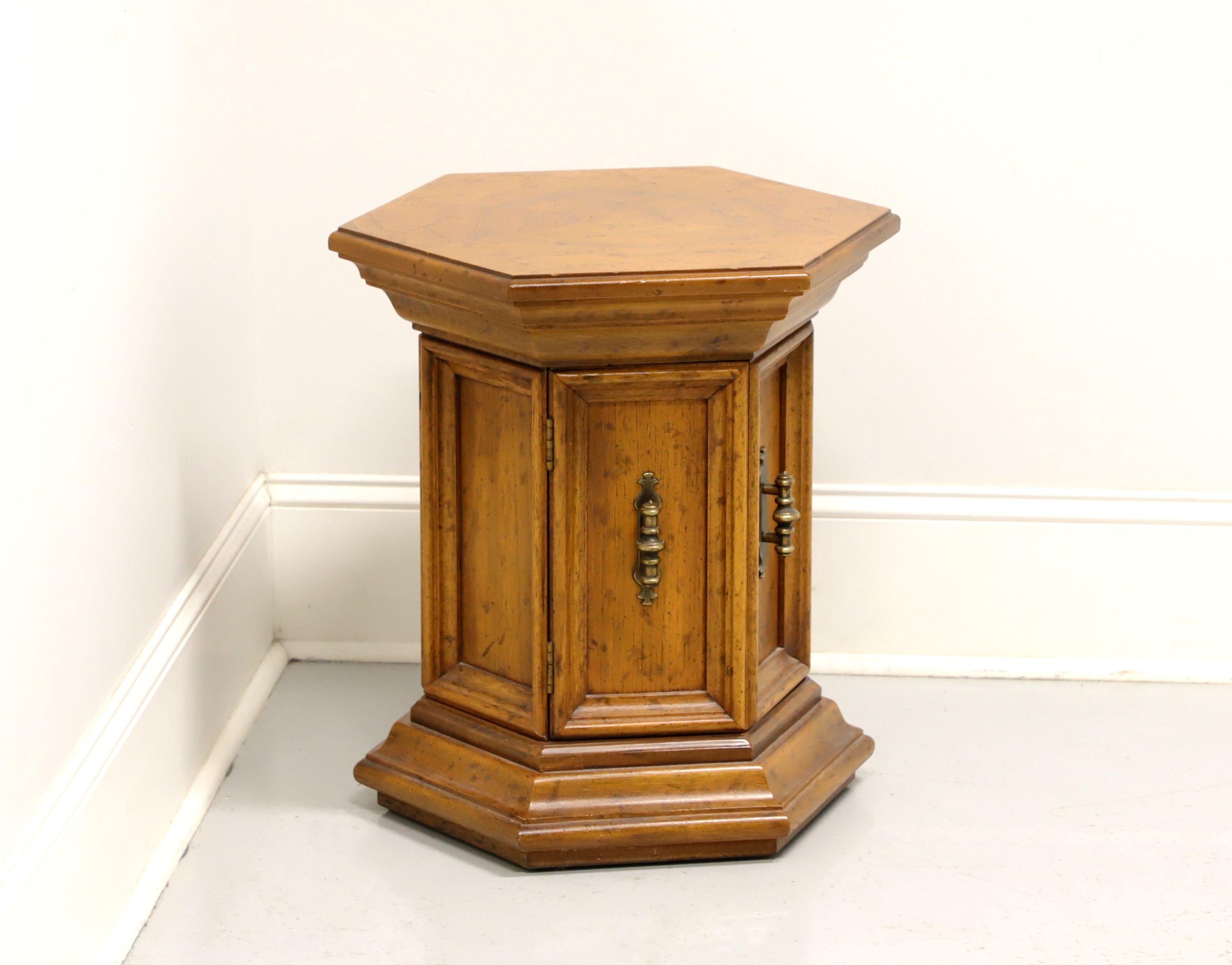 A Spanish style hexagonal shaped cabinet accent table by Drexel, from their Velero Collection. Pecan with a distressed finish, inlaid top and brass hardware. Features a two door cabinet revealing a small storage area. Made in North Carolina, USA,