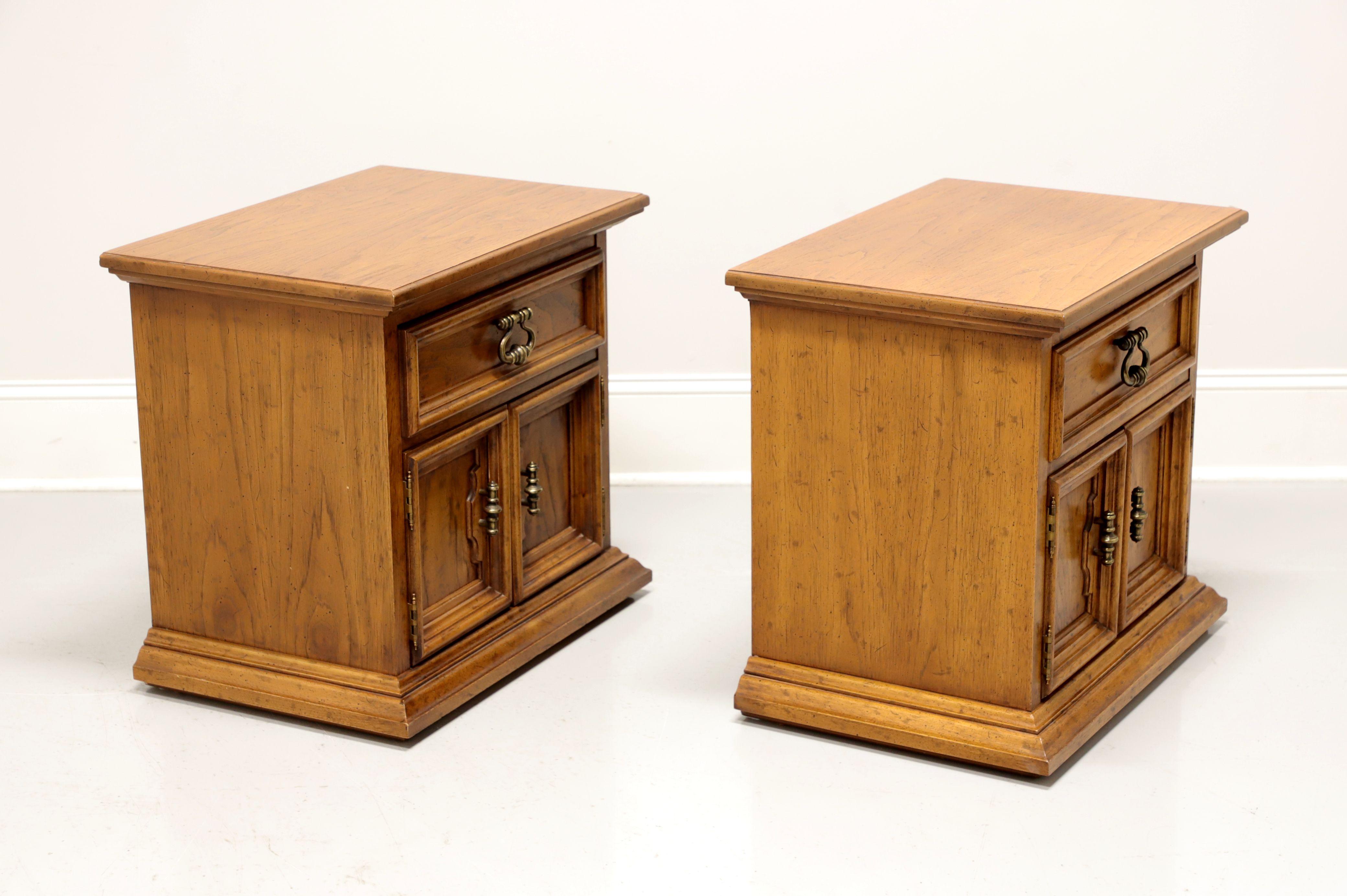 A pair of Spanish style nightstands by Drexel, from their Velero Collection. Pecan with a distressed finish and brass hardware. Features one drawer of dovetail construction over a two door cabinet revealing a storage area. Made in North Carolina,