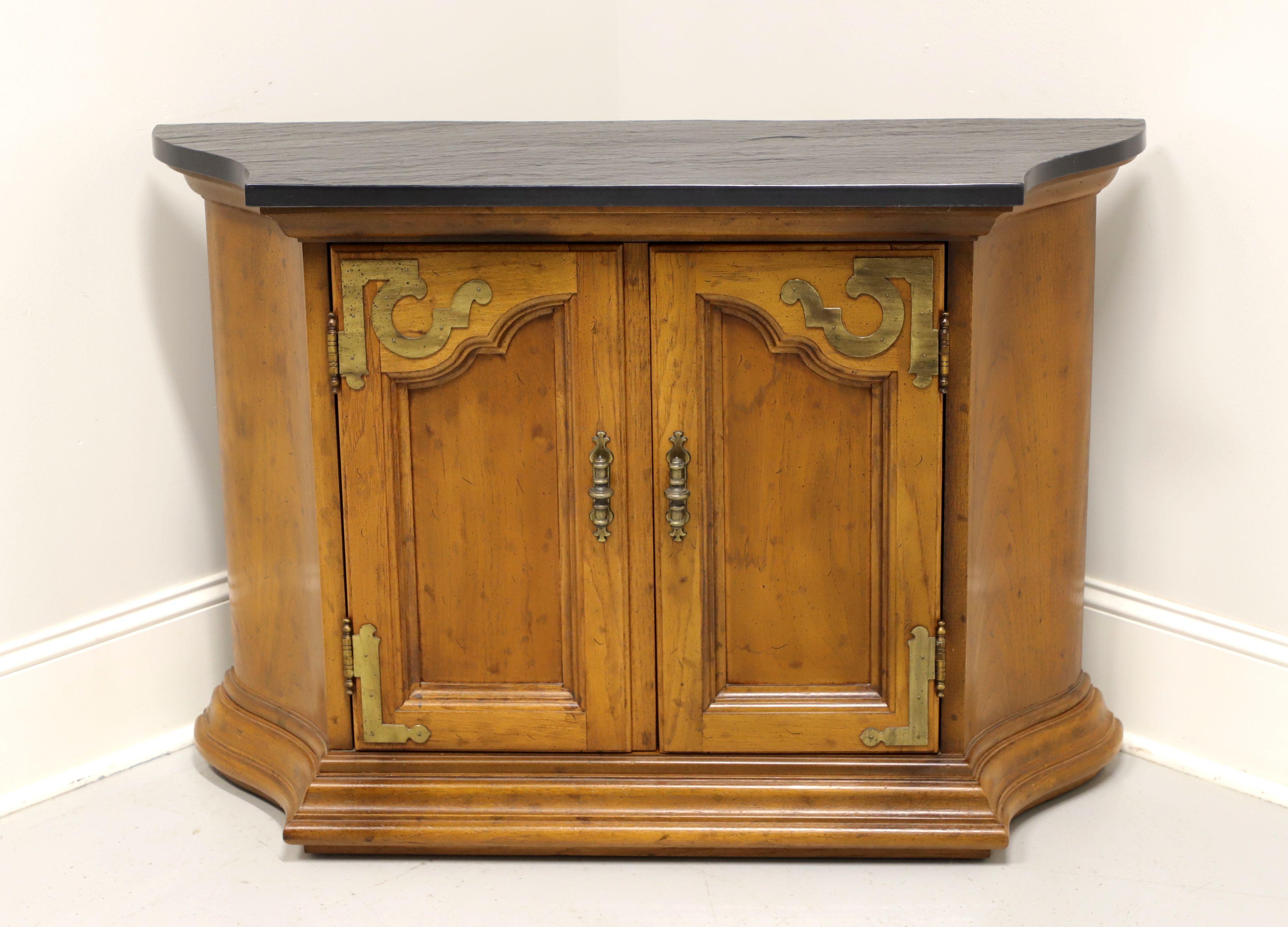 A Spanish style console cabinet by Drexel, from their Velero Collection. Pecan with a distressed finish, slate top and brass hardware. Features a two door cabinet revealing a storage area with one adjustable wood shelf. Made in North Carolina, USA,