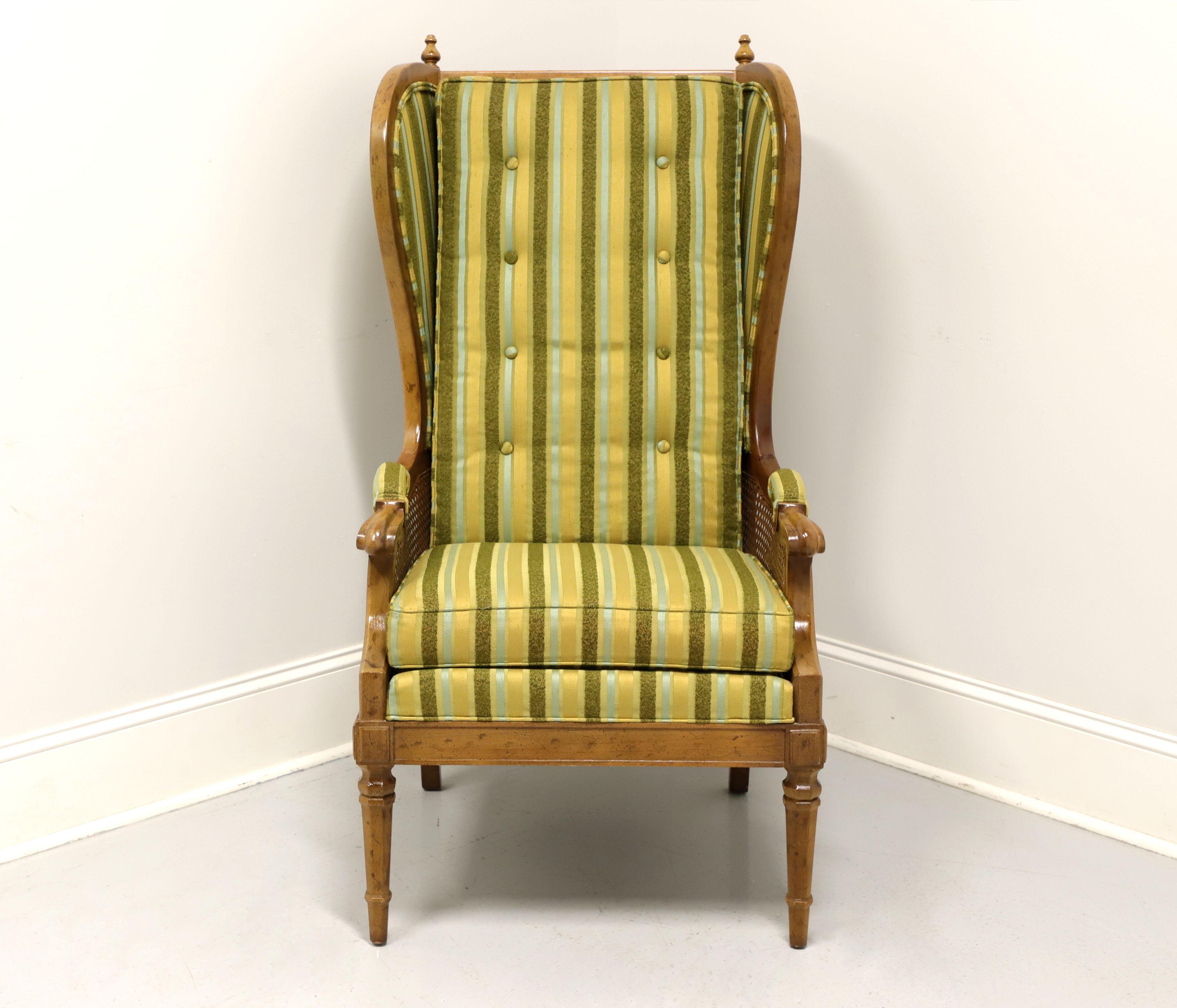 A Spanish style wing back chair by Drexel, from their Velero Collection. Pecan with a distressed finish, finials to crest rail, upholstered arm rests, cane to sides of arms and round tapered front legs. Green, gold, lime green and teal color striped