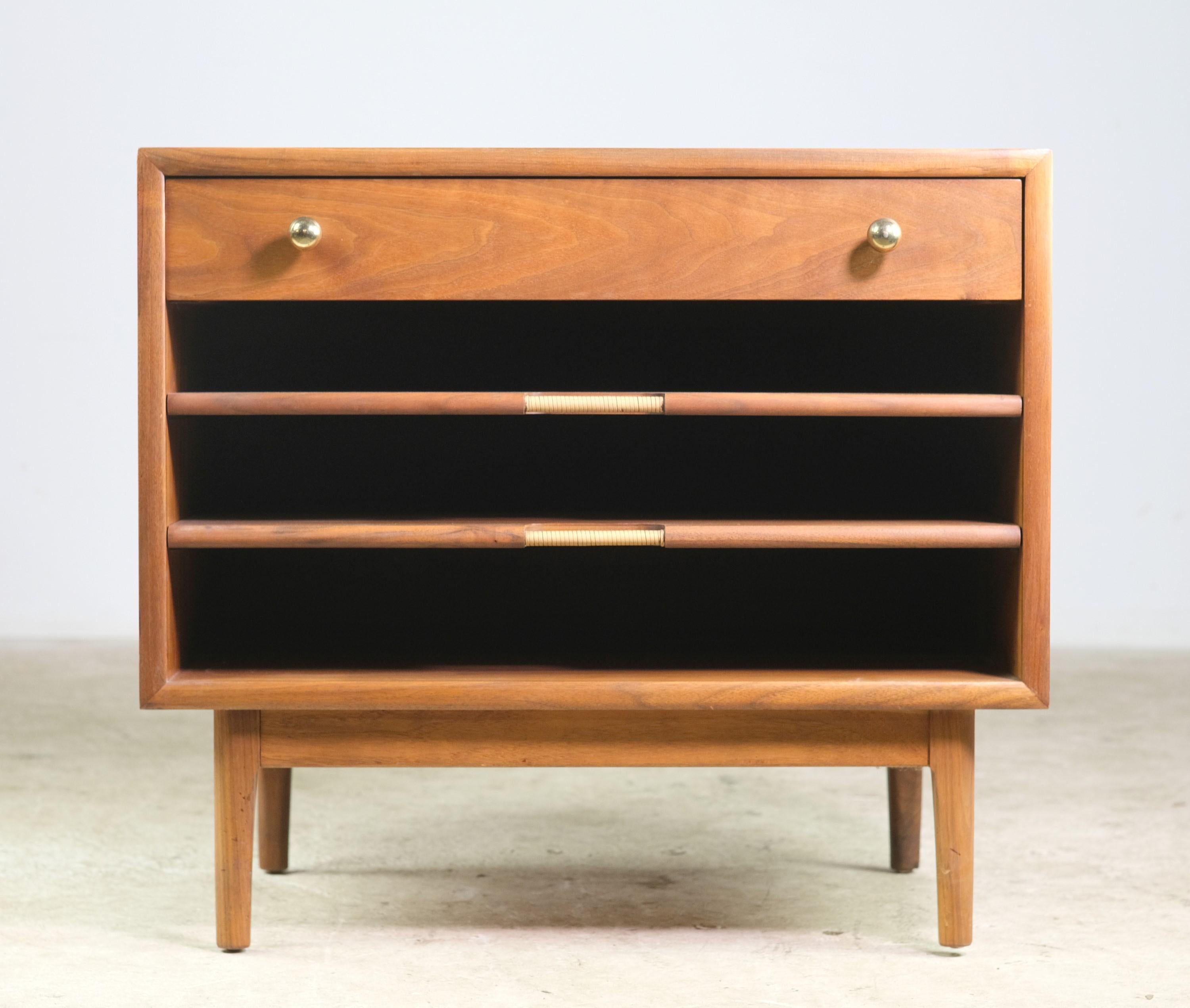 Made by Drexel, Mid-Century Modern walnut end table with one drawer and two shelves. The drawer has the original brass knobs and below are the two slide shelves. There is some worn finish on top & a small veneer chip on corner. Please see the