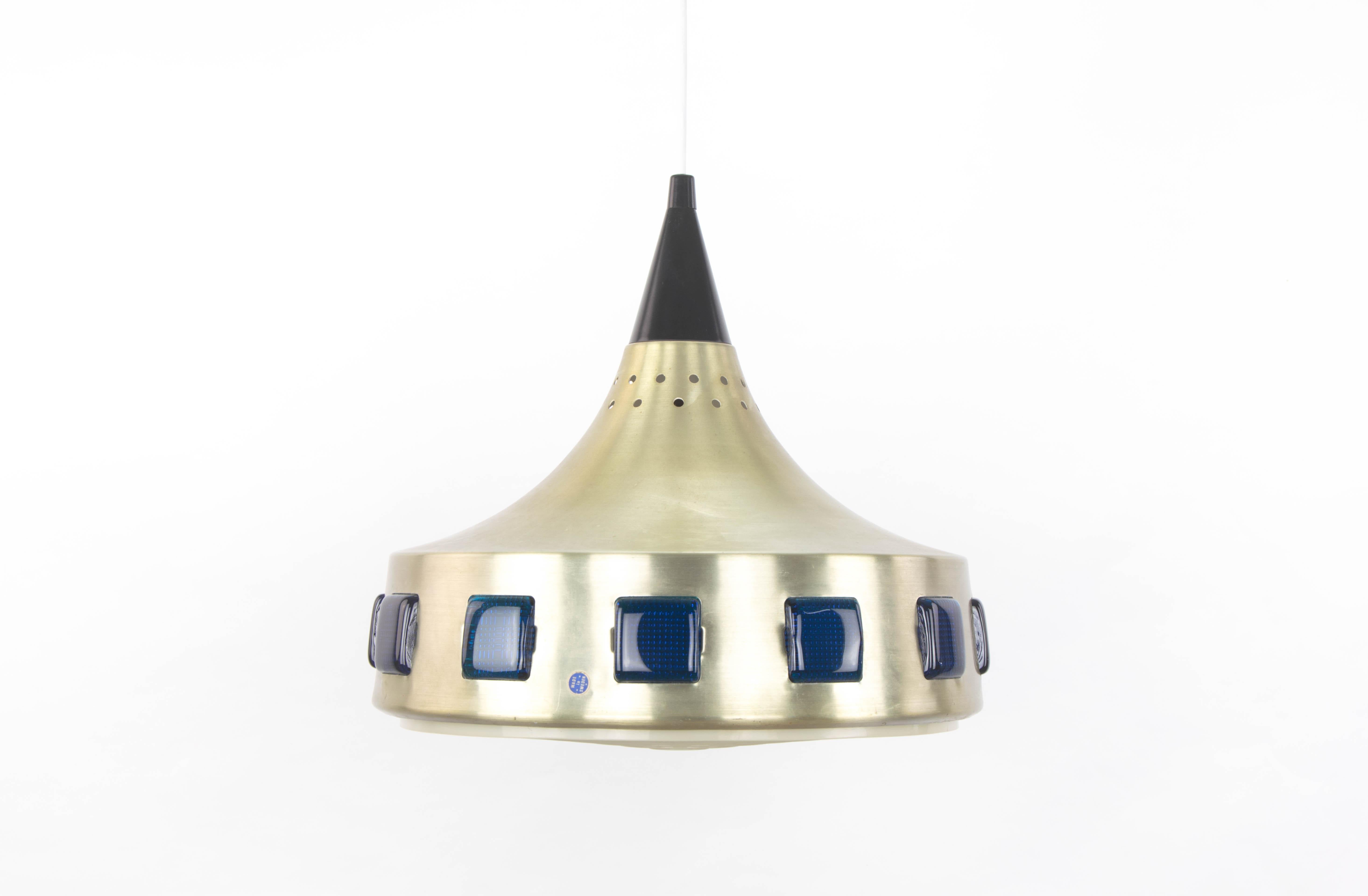Lampada da soffitto svedese UFO del marchio DRGM. Corpo in alluminio anodizzato placcato oro con cristalli blu e diffusore in plastica dura. Presenta aree di usura nella finitura dorata.
Misure:
Altezza totale 116 cm
Corpo alto 32 cm
Diametro