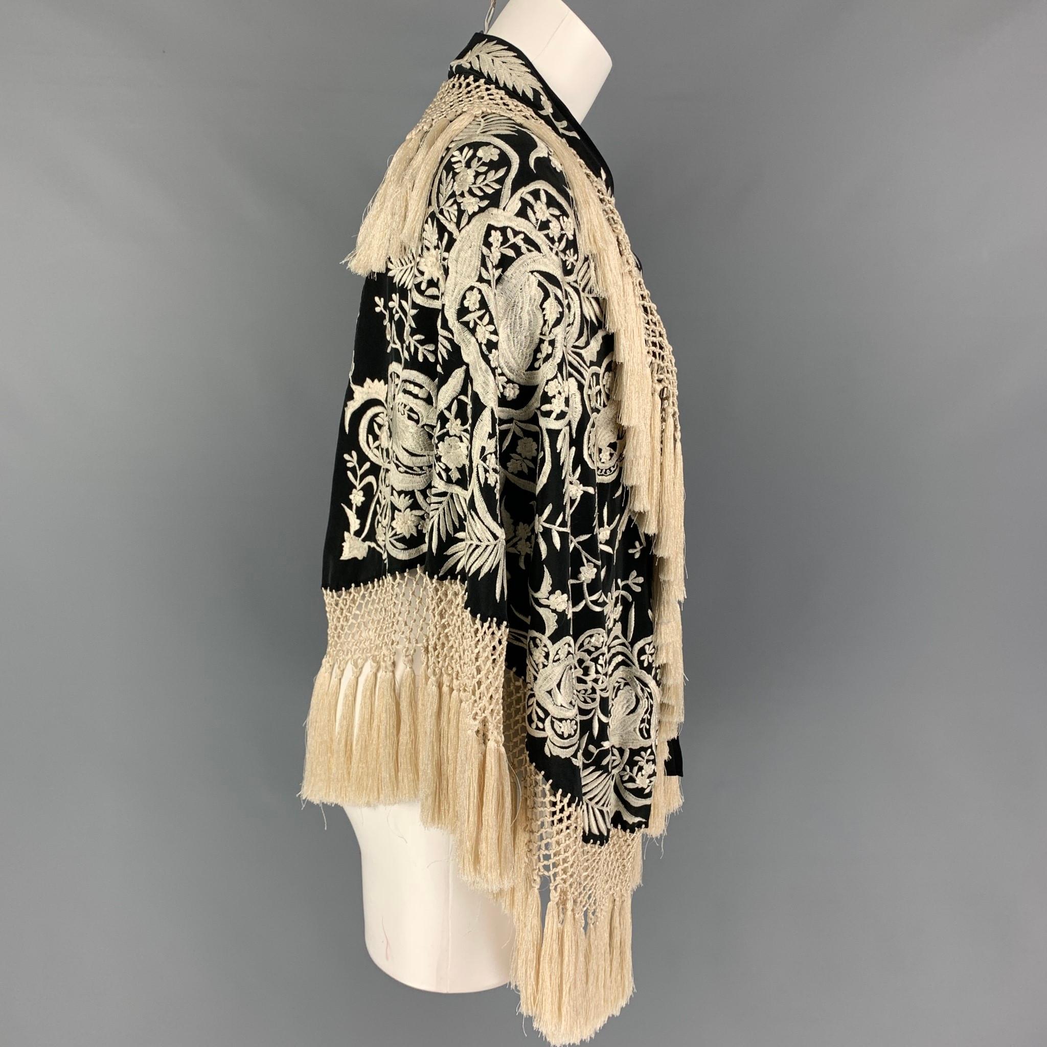 DRIES VAN NOTEN cape comes in a black & cream silk featuring embroidered designs, fringe tassels, and a self-tie closure. 

Very Good Pre-Owned Condition.
Marked: One Size

Measurements

Length: 26 in. 