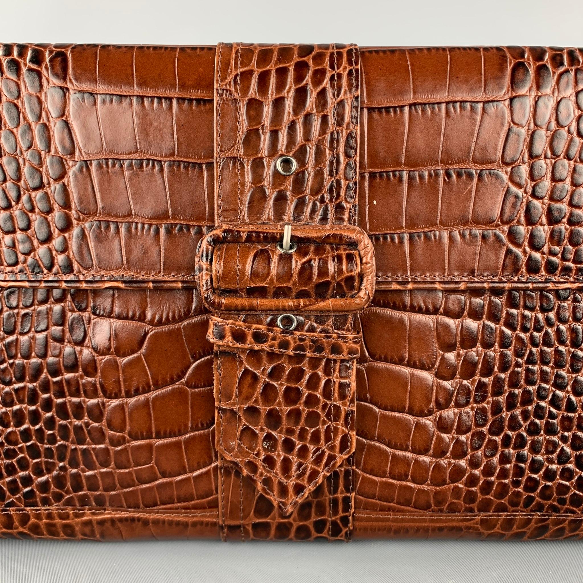 DRIES VAN NOTEN clutch comes in a brown embossed alligator featuring a front strap design, inner slot, and a magnet closure. 

Very Good Pre-Owned Condition.

Measurements:

Length: 12.5 in.
Width: 1.5 in.
Height: 7 in.
 