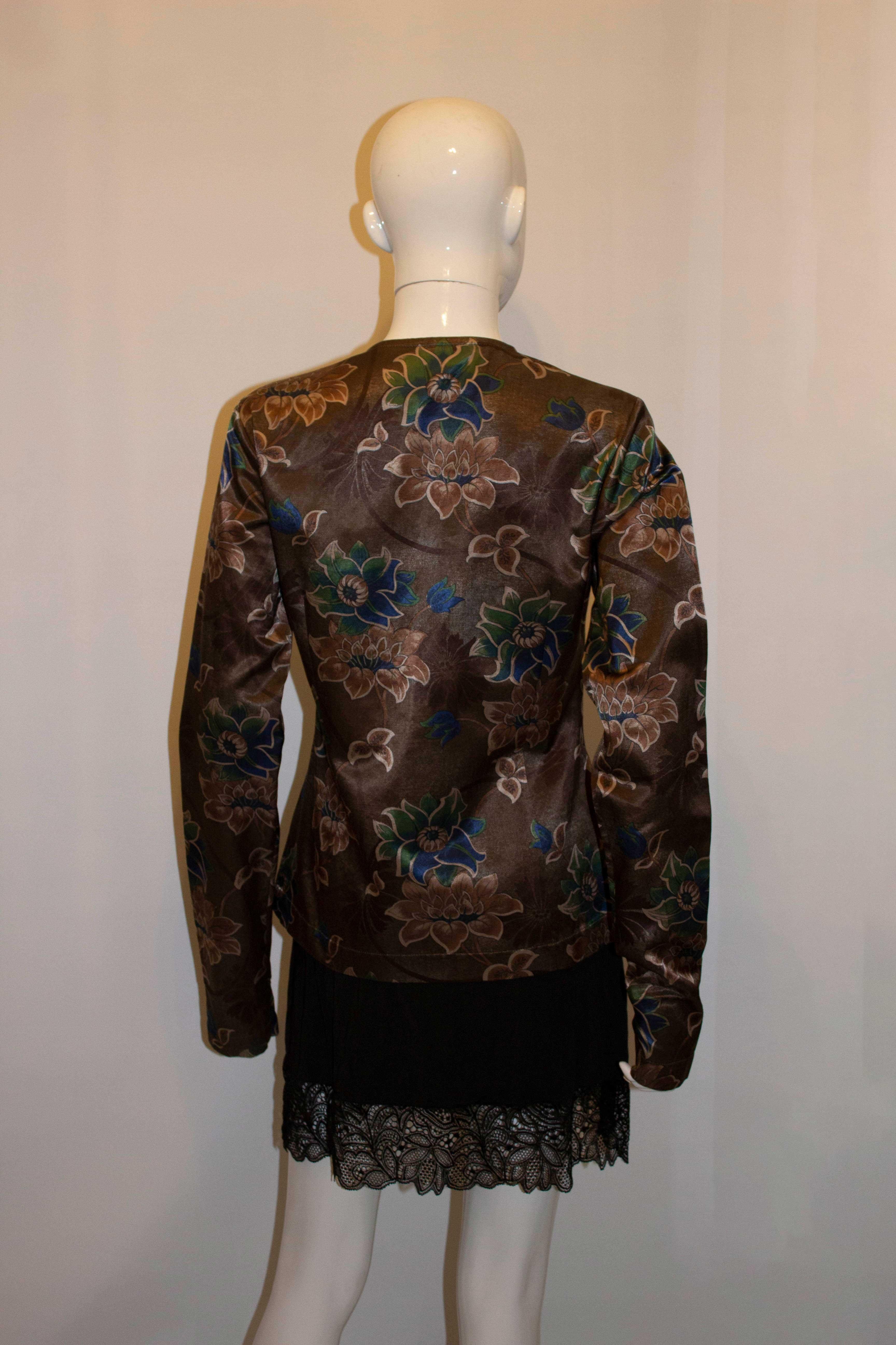 A pretty jacket / top by Dres van Noten. The jacket has an olive background , with a floral print. It has a round neck with a hook and eye fastening. Made in Belgium, size 38. Measurements: Bust up to 38'', length 25''.