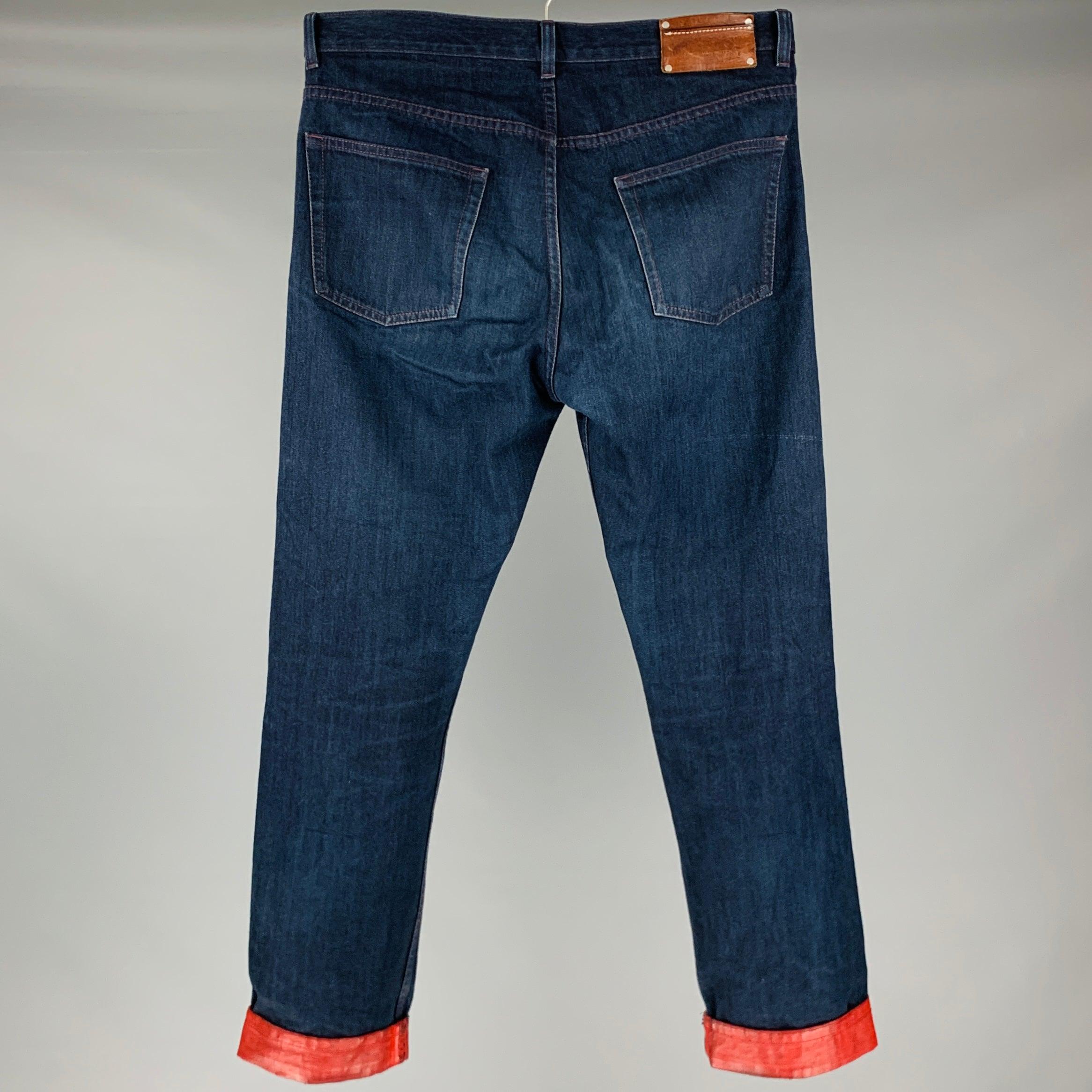 DRIES VAN NOTEN jeans in a navy cotton fabric featuring painted red cuff details, five pocket style, and zip fly closure. Very Good Pre-Owned Condition. Minor signs of wear. 

Marked:   30 

Measurements: 
  Waist: 30 inches Rise: 9 inches Inseam: