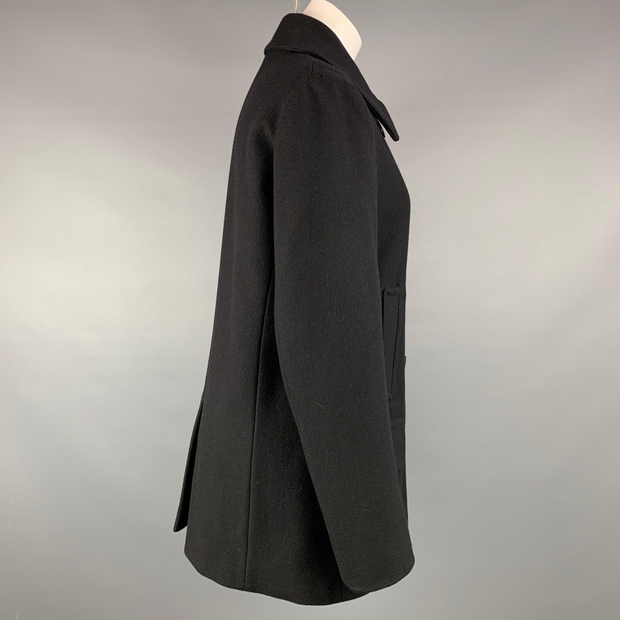 Der Mantel von DRIES VAN NOTEN ist aus einer schwarzen Wollmischung gefertigt und verfügt über einen spitzen Kragen, Pattentaschen und einen doppelten Brustverschluss.
Sehr gut
Gebrauchtes Zustand. 

Markiert:  L 

Abmessungen: 
 
Schultern: 16 Zoll
