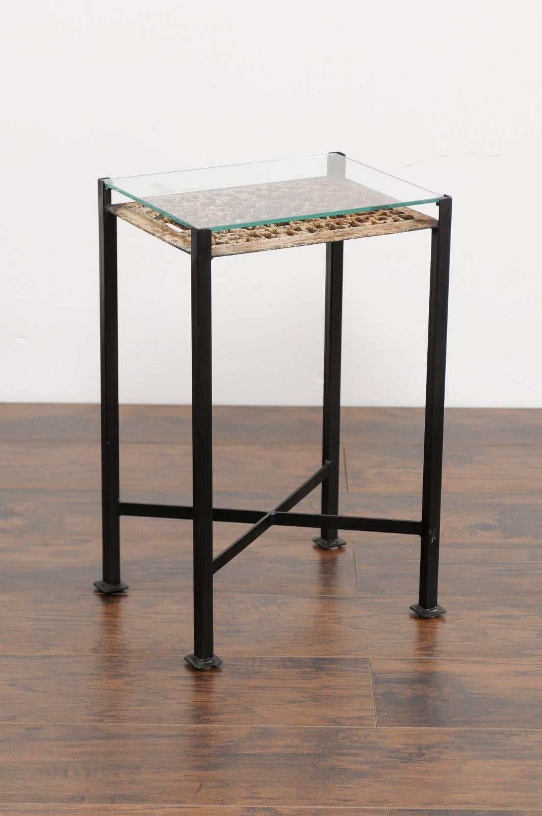 A small rectangular drink table made from a French decorative iron fretwork ornament from the first half of the 20th century, protected by a custom glass top and mounted on a 21st century custom base. This small drink table features a rectangular