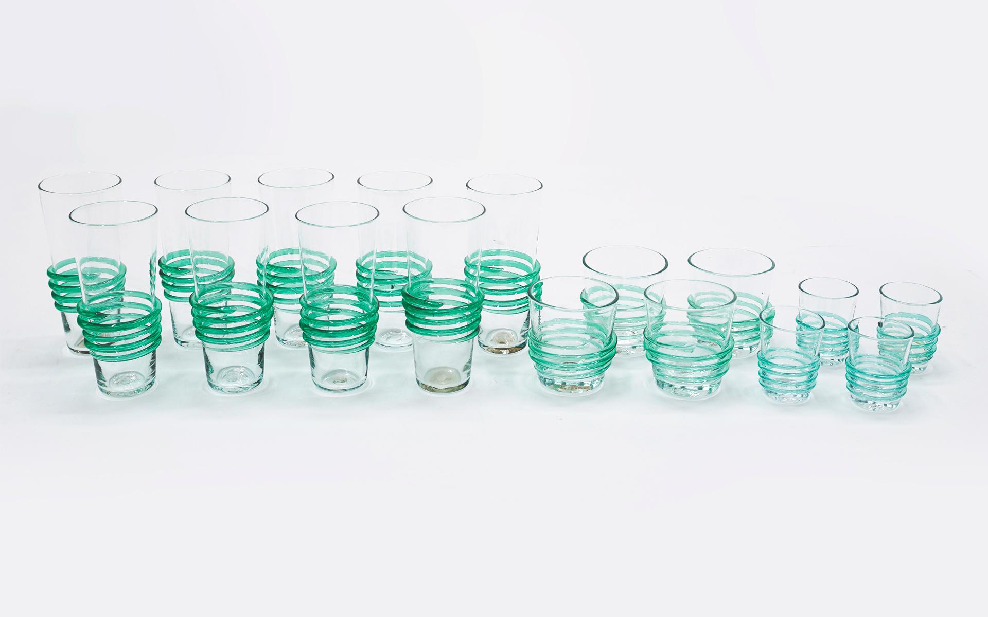 Set of seventeen Blenko hand blown glasses. Nine drinking glasses, four hi-ball glasses and four shot glasses. All with applied spiraling green glass which is both decorative and functional for your hand to hold the glass. No chips, cracks, or wear.