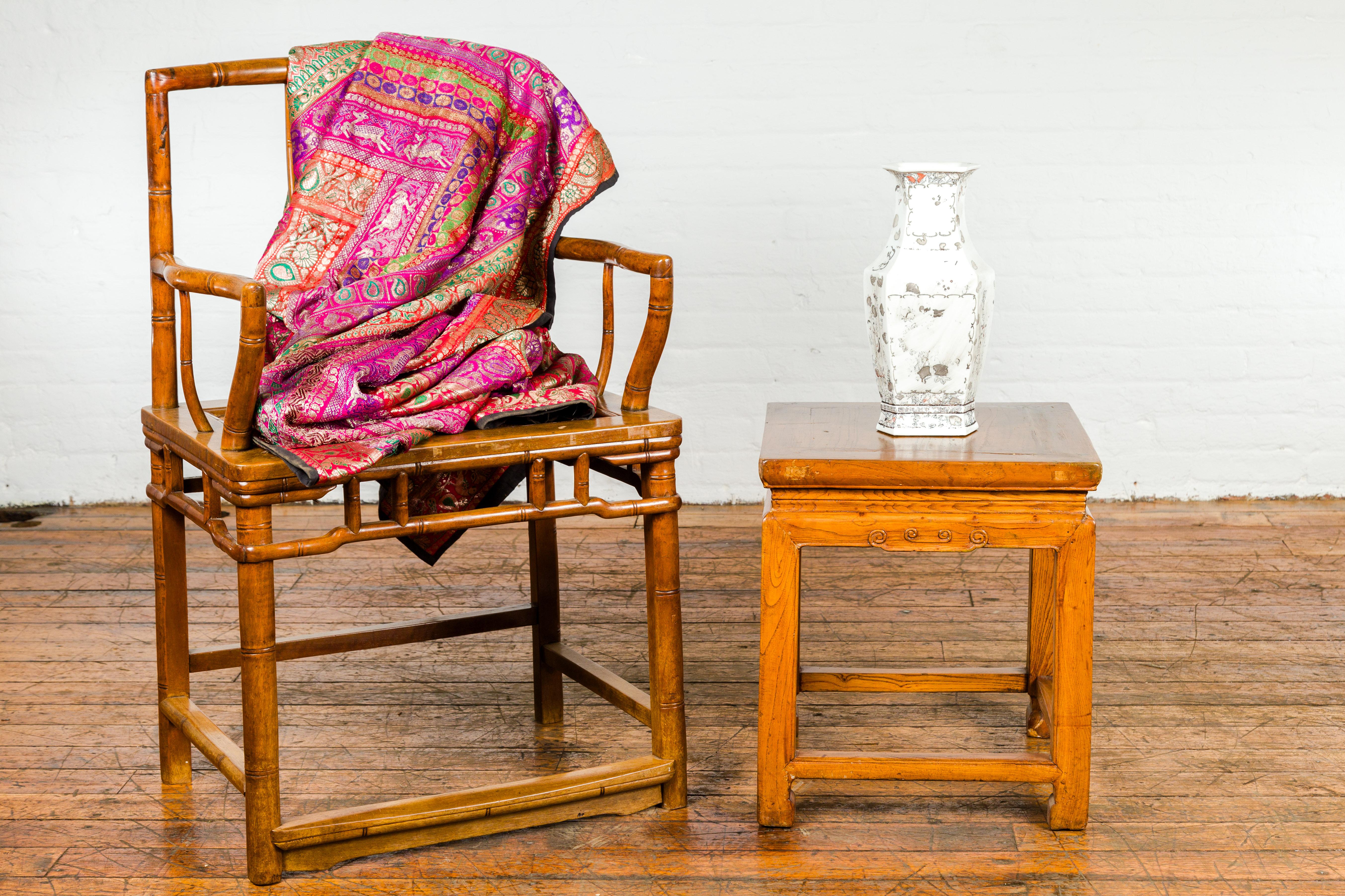 A small late Qing Dynasty period side table or stool from the early 20th century with waisted top, carved apron, horse hoof legs and side stretchers. Exuding age-old artisanship, this late Qing Dynasty side table, or stool, is a perfect mix of