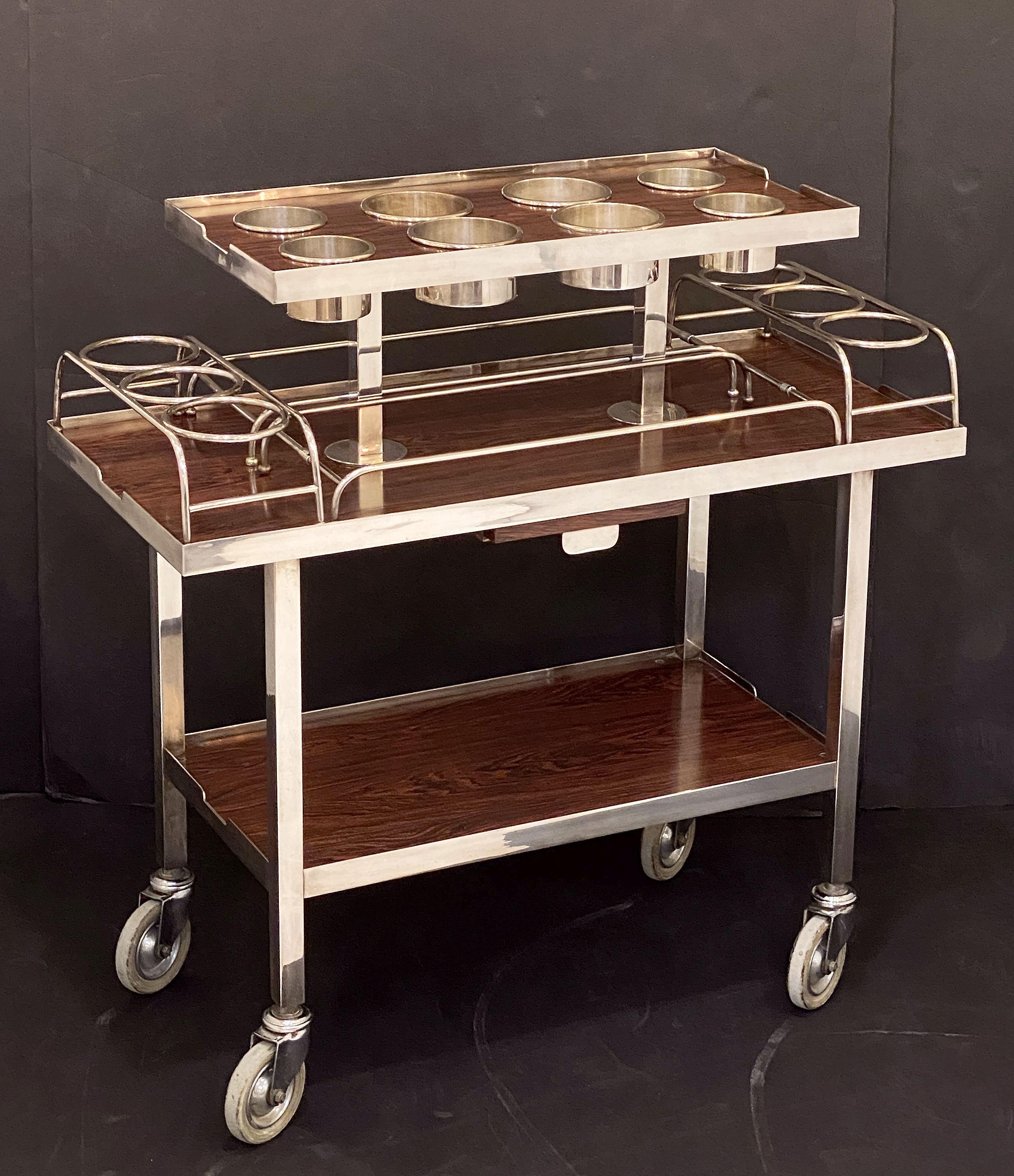 A fine Mid-Century silver-plated and chrome drinks trolley from the Ritz Hotel, London, by Drakes Silversmiths of London - featuring three faux rosewood tiers, with eight removable bottle holder basins to top tier and four removable racks to the