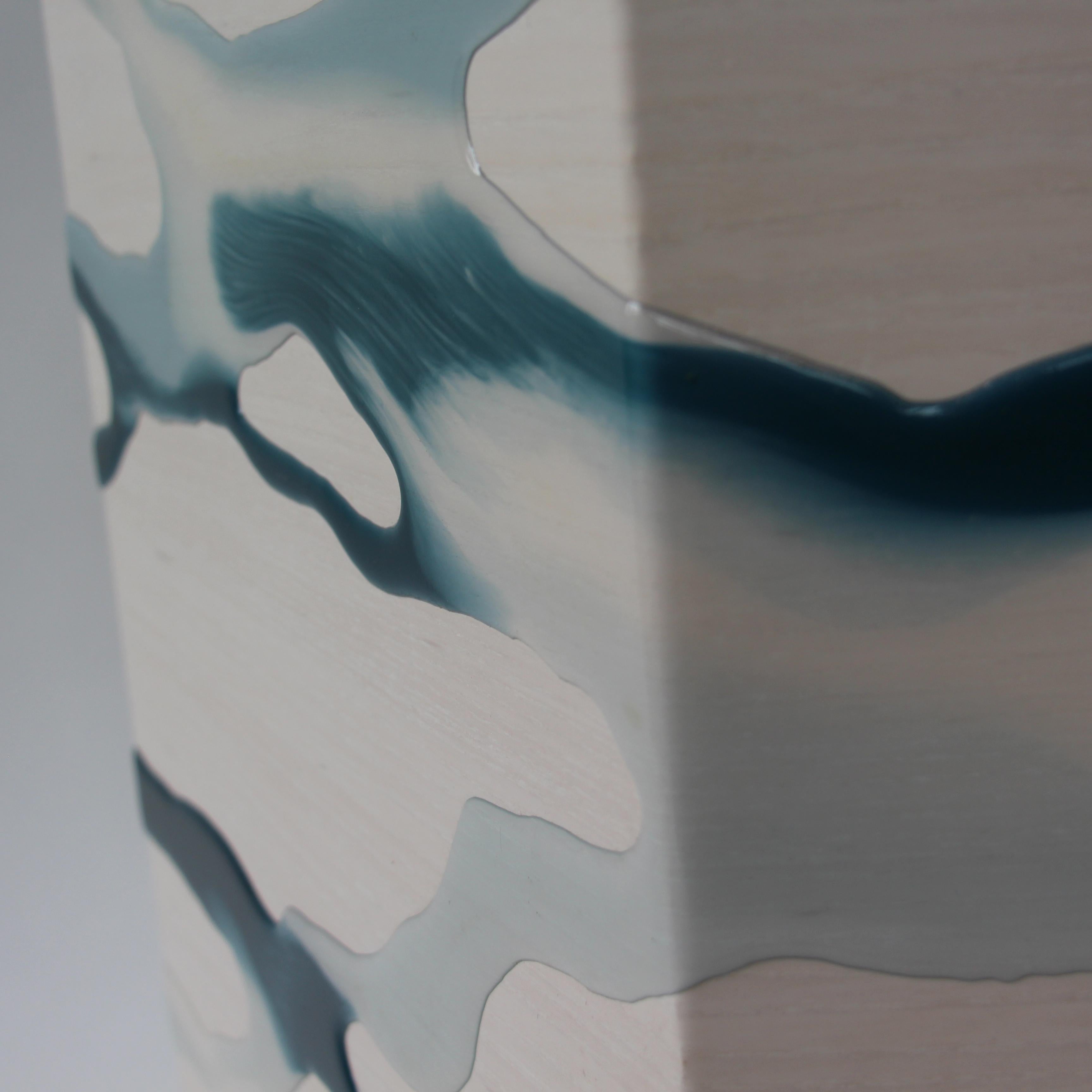 The drip/fold side table by Noble Goods is constructed of a single sheet of whitened ash plywood that has been hand-dripped with liquid resin, then bent into a hexagonal shape. 

This unique resin colorway has subtle tones of blue, teal and black,