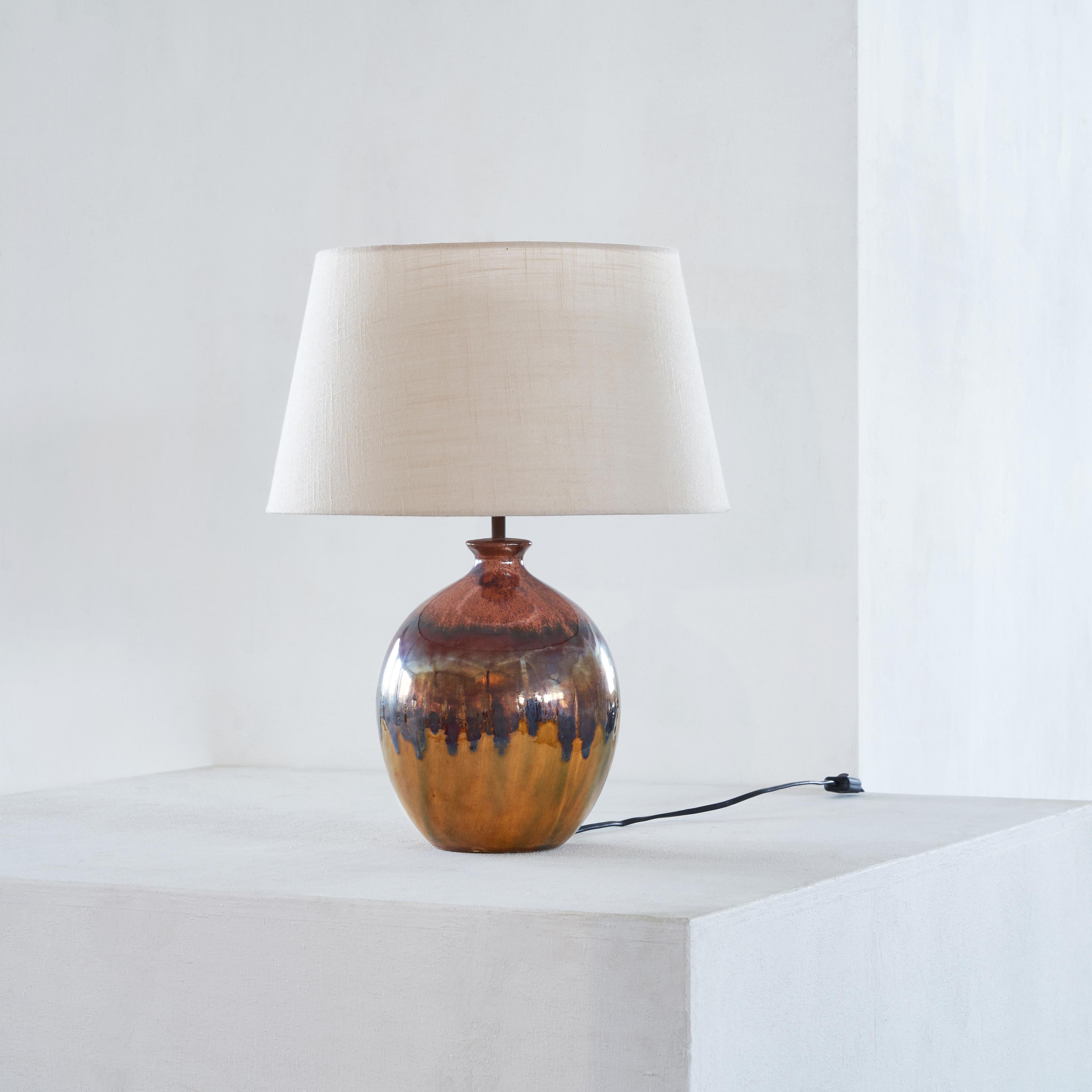 Drip Glazed Mid-Century Modern table lamp

This characteristic table lamp has a handmade ceramic spherical base, showing a drip glazed surface in different warm tones. The top of the base has a bottle like shape, holding the lighting element and