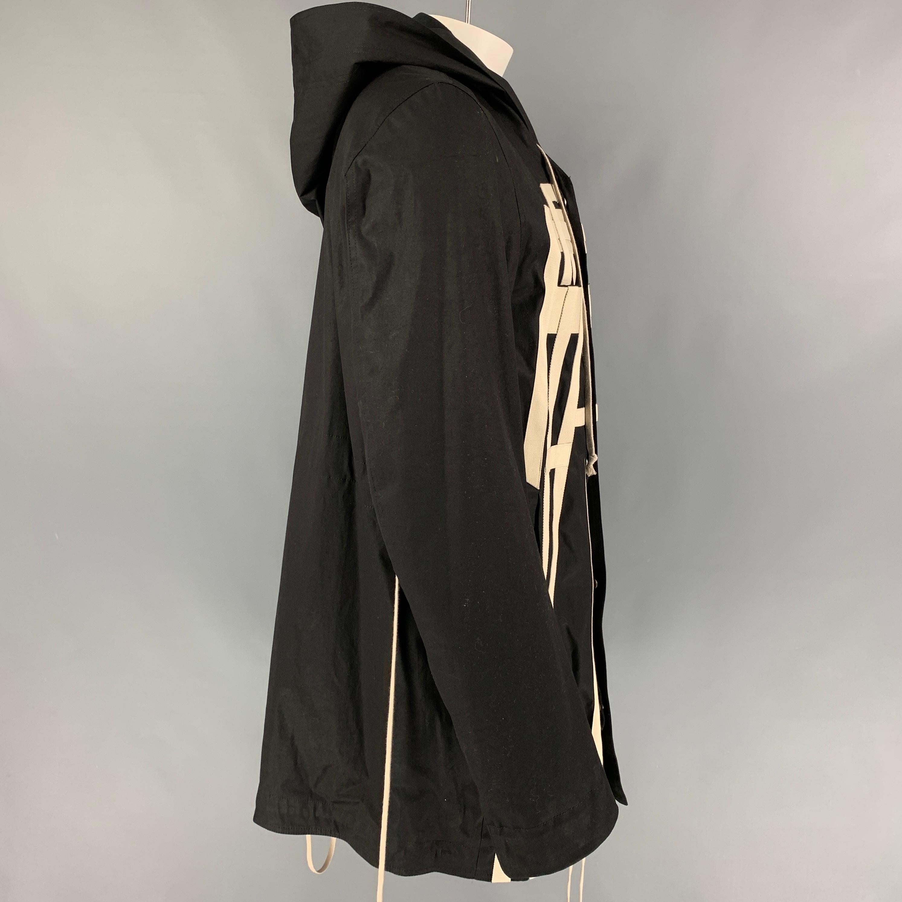 DRKSHDW by RICK OWENS coat comes in a black cotton featuring signature cream canvas strap details, hooded, front pockets, hooded, single back vent, and a zip & snap button closure. Includes tote bag. Made in Italy. 

Excellent Pre-Owned