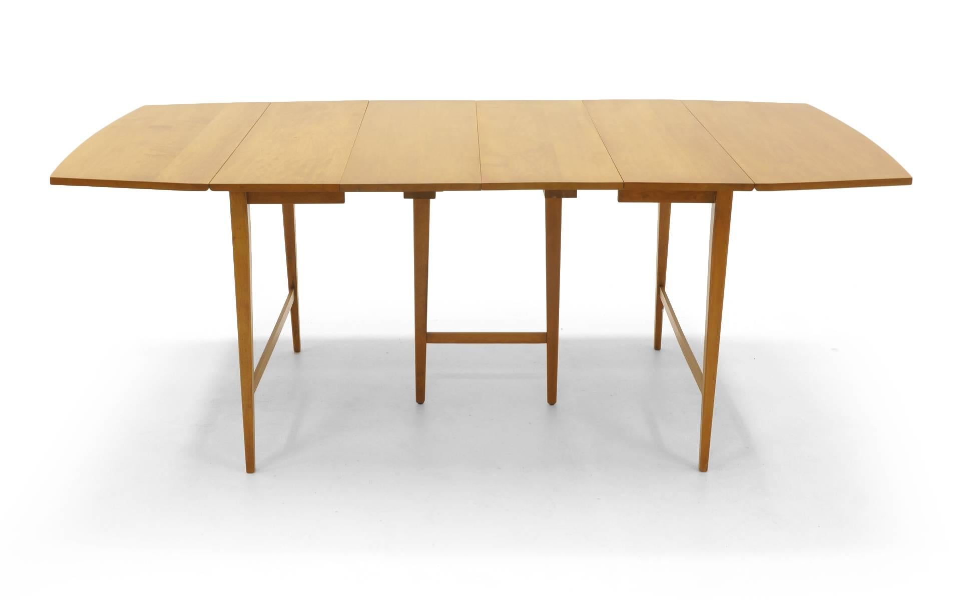 Paul McCobb drop-leaf dining table with center legs for Winchendon Modern with three additional leaves. At its smallest, the table is 24 inch by 40 inch table for two. Each drop-leaf is 15 inches so it extends to 39 inches with one leaf up and 54